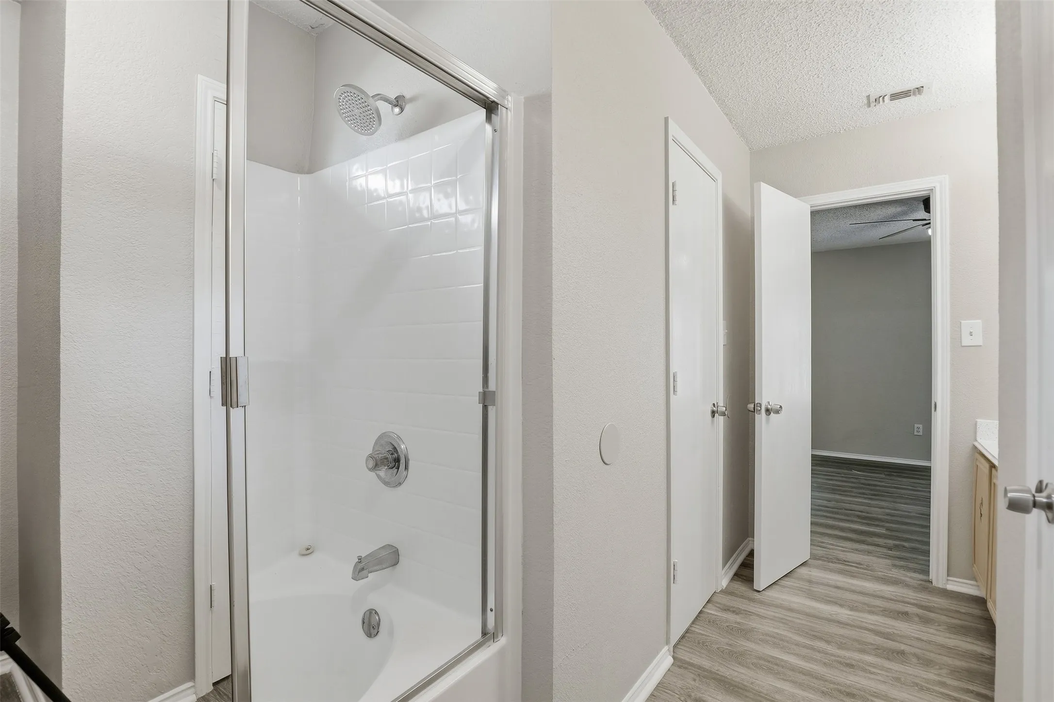 Bath with a tub/shower combination, clear glass enclosure, and chrome fixtures