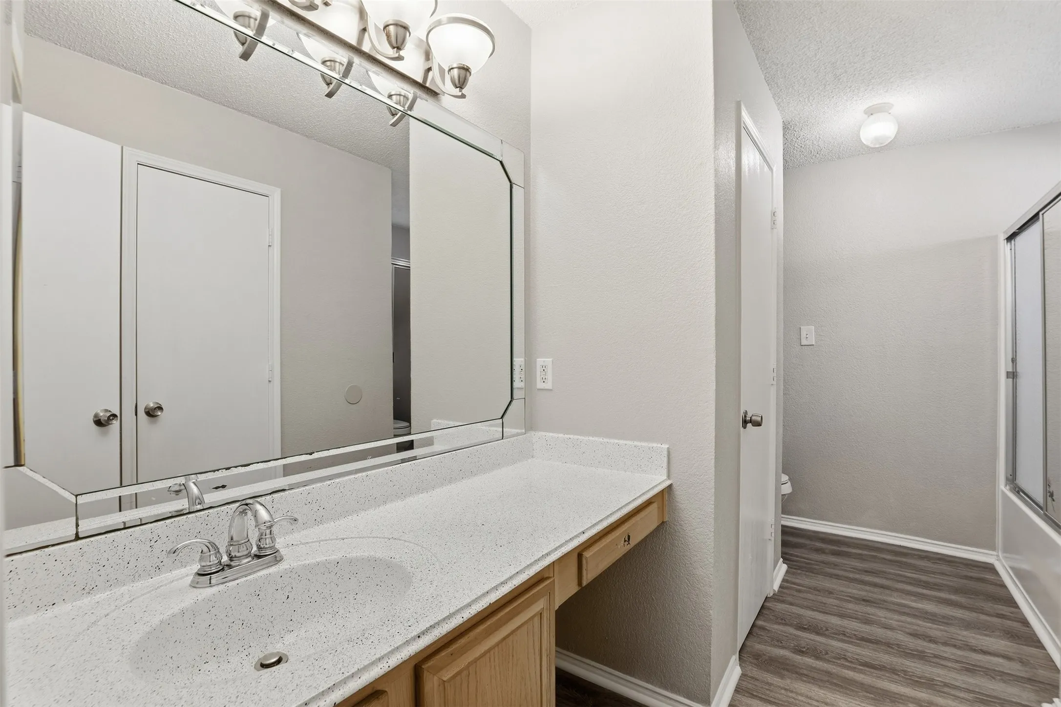 Vanity with integrated sink, chrome faucet, and expansive wall-mounted mirror