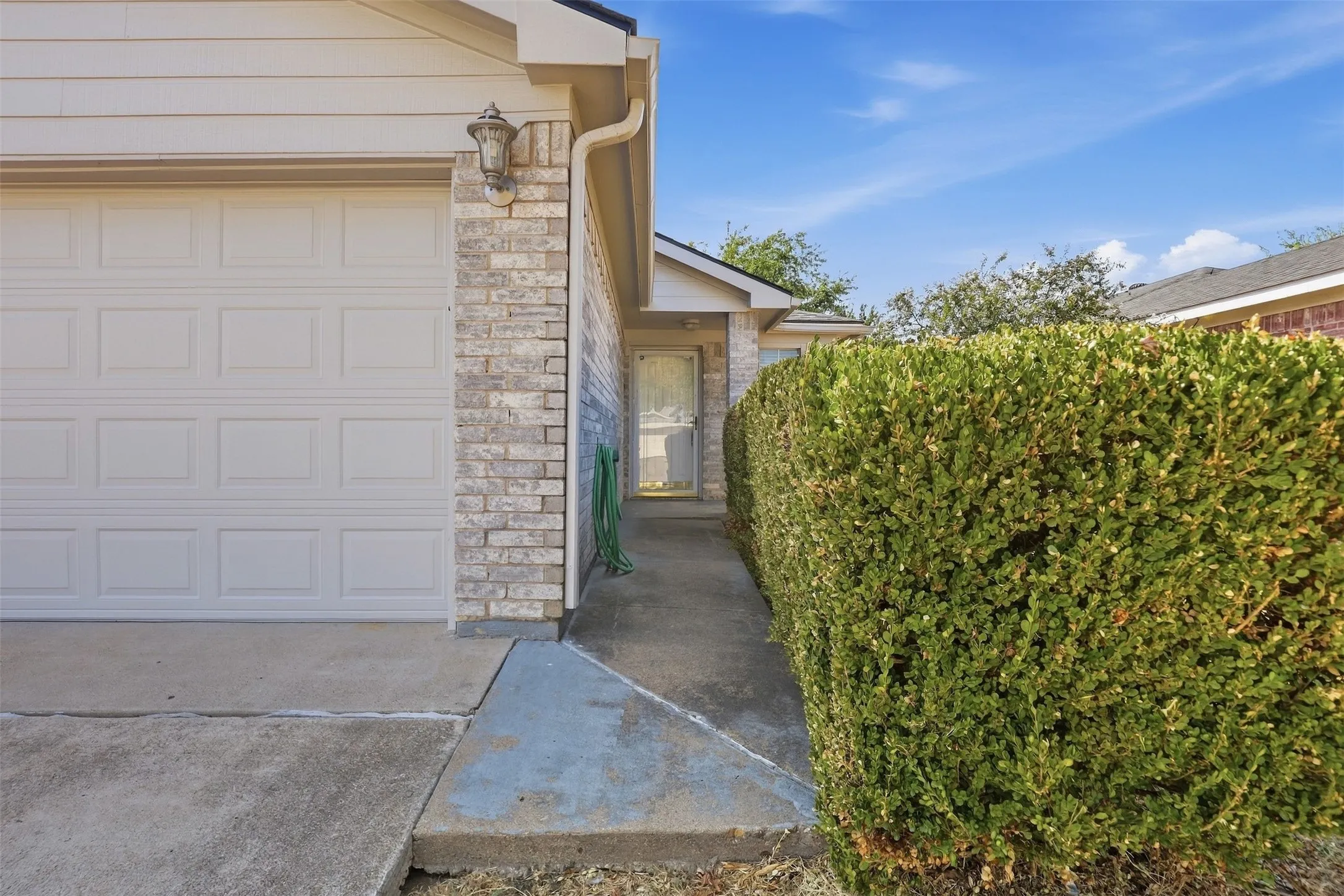 Brick and siding exterior with an attached garage, featuring a concrete driveway and walkway