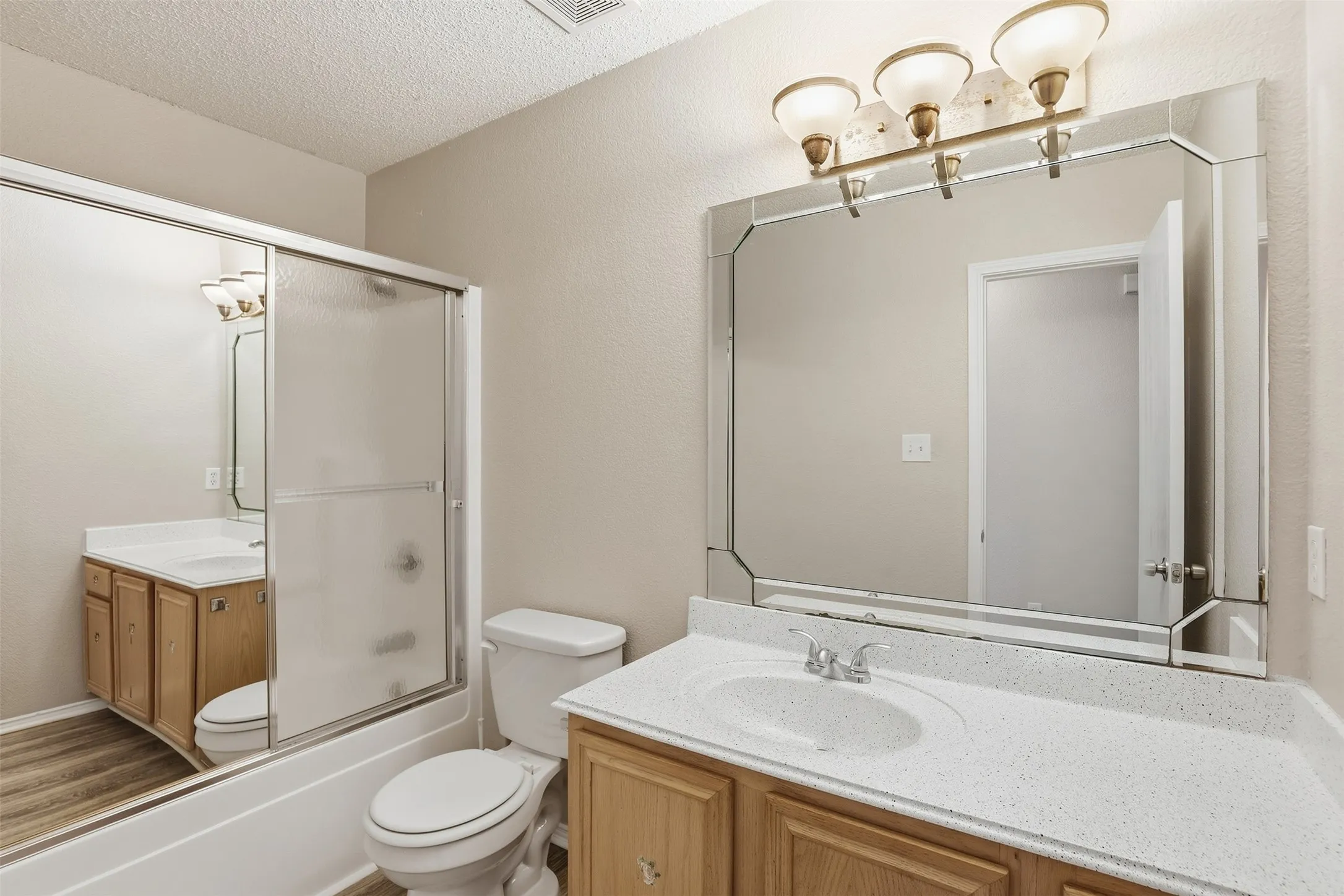 Bathroom featuring a single vanity with light-toned cabinetry, light speckled countertop, and an integrated sink