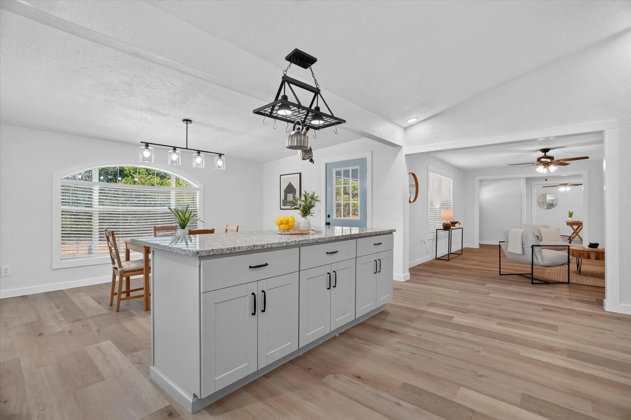 Kitchen island with stone-finish countertop, wood-finish flooring, recessed lighting, and a decorative light fixture