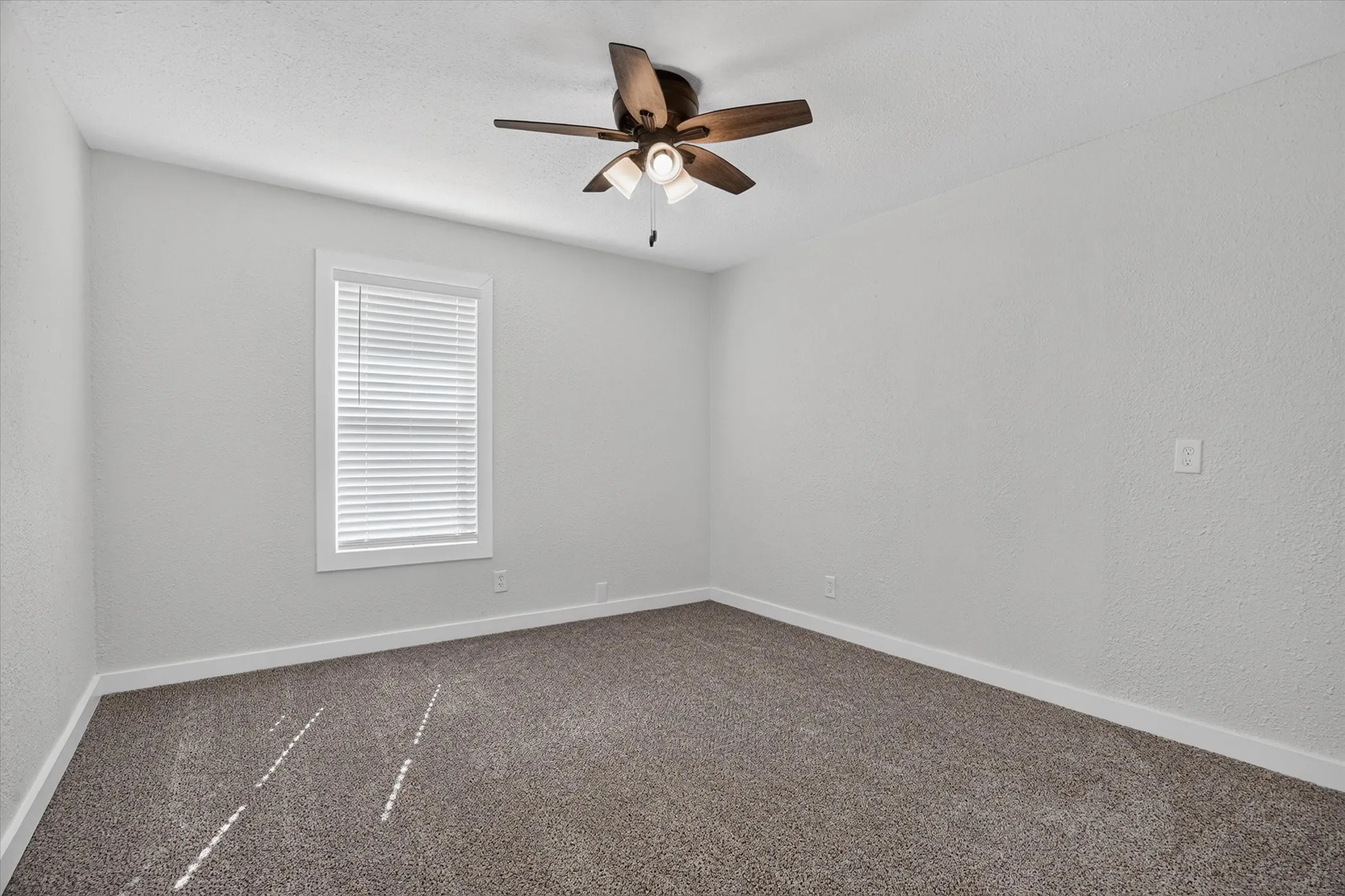 Carpeted room featuring a ceiling fan with integrated lighting
