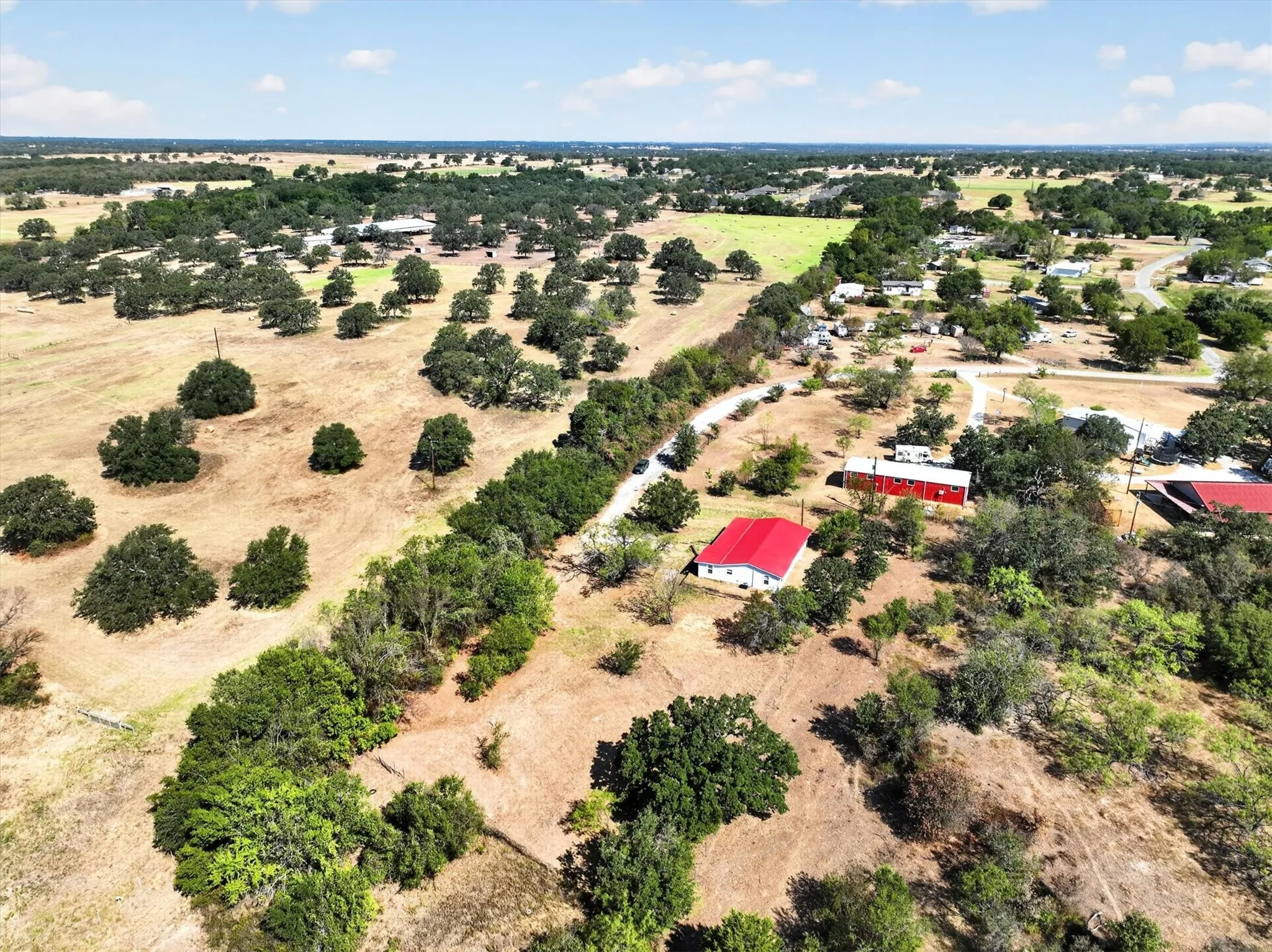 Expansive property featuring mature trees, a red-roofed residence, and a red-sided​​‌​​​​‌​​‌‌​‌‌​​​‌‌​‌​‌​‌​​​‌​​ outbuilding