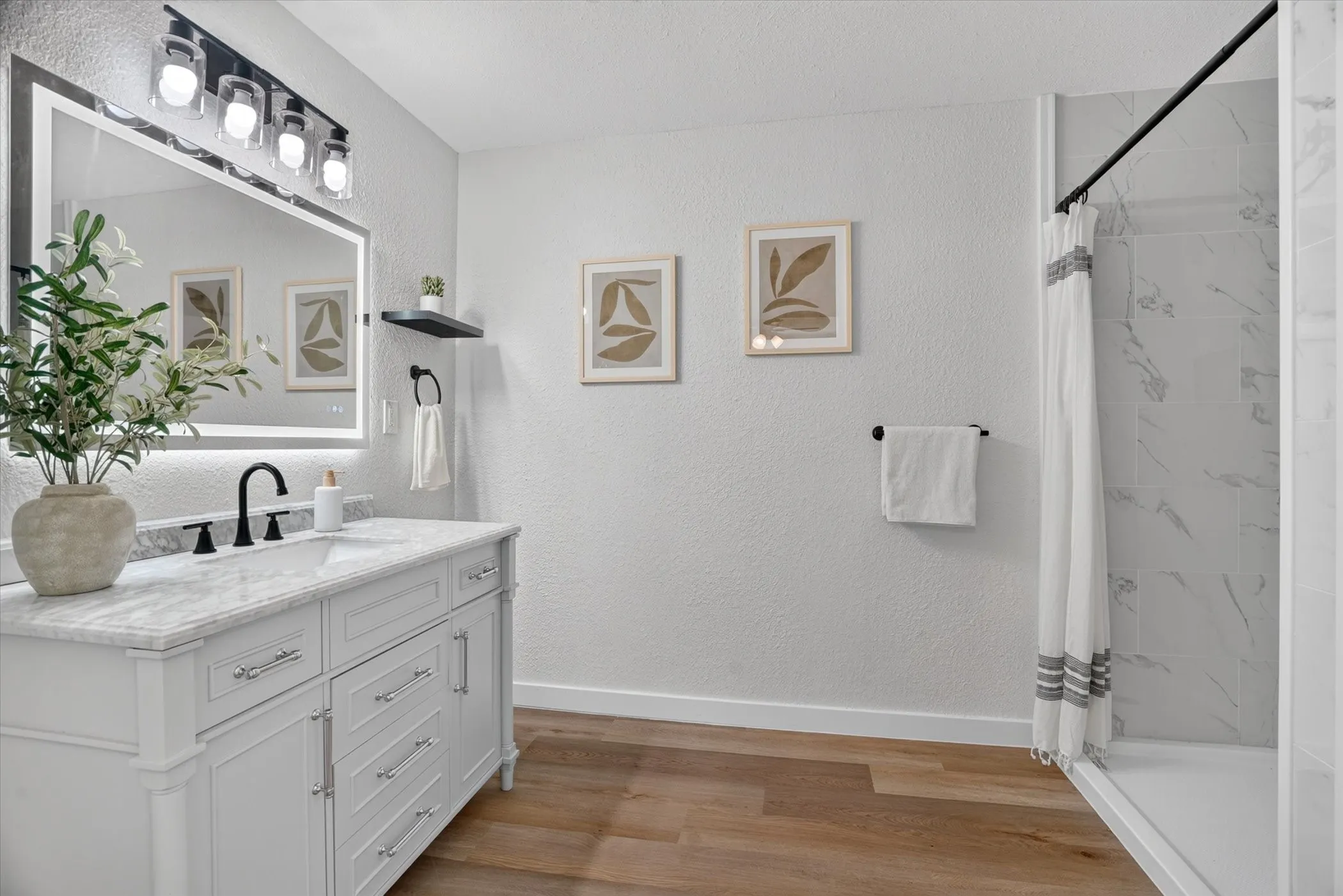 White shaker vanity with a light-colored countertop, integrated sink, and black fixtures