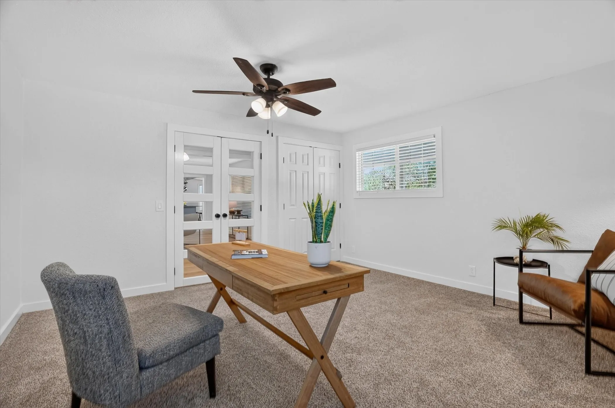 Carpeted room featuring a ceiling fan with integrated lighting, glass-paneled French doors, a window with horizontal blinds, and a solid panel door