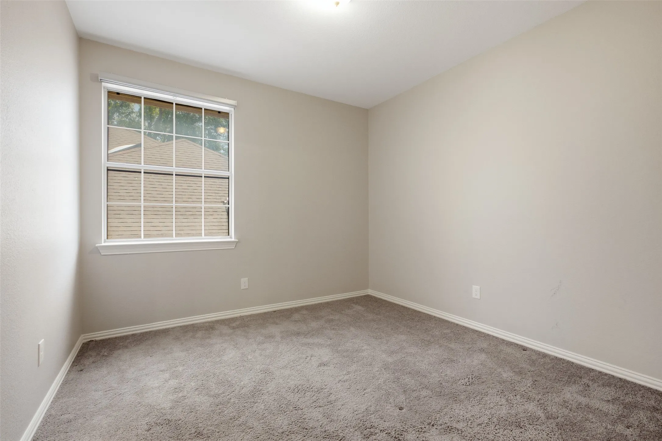 A well-sized secondary bedroom upstairs with plush carpet, neutral walls, and a window overlooking the neighborhood. Works equally well as a guest room, kids' room, or home office.