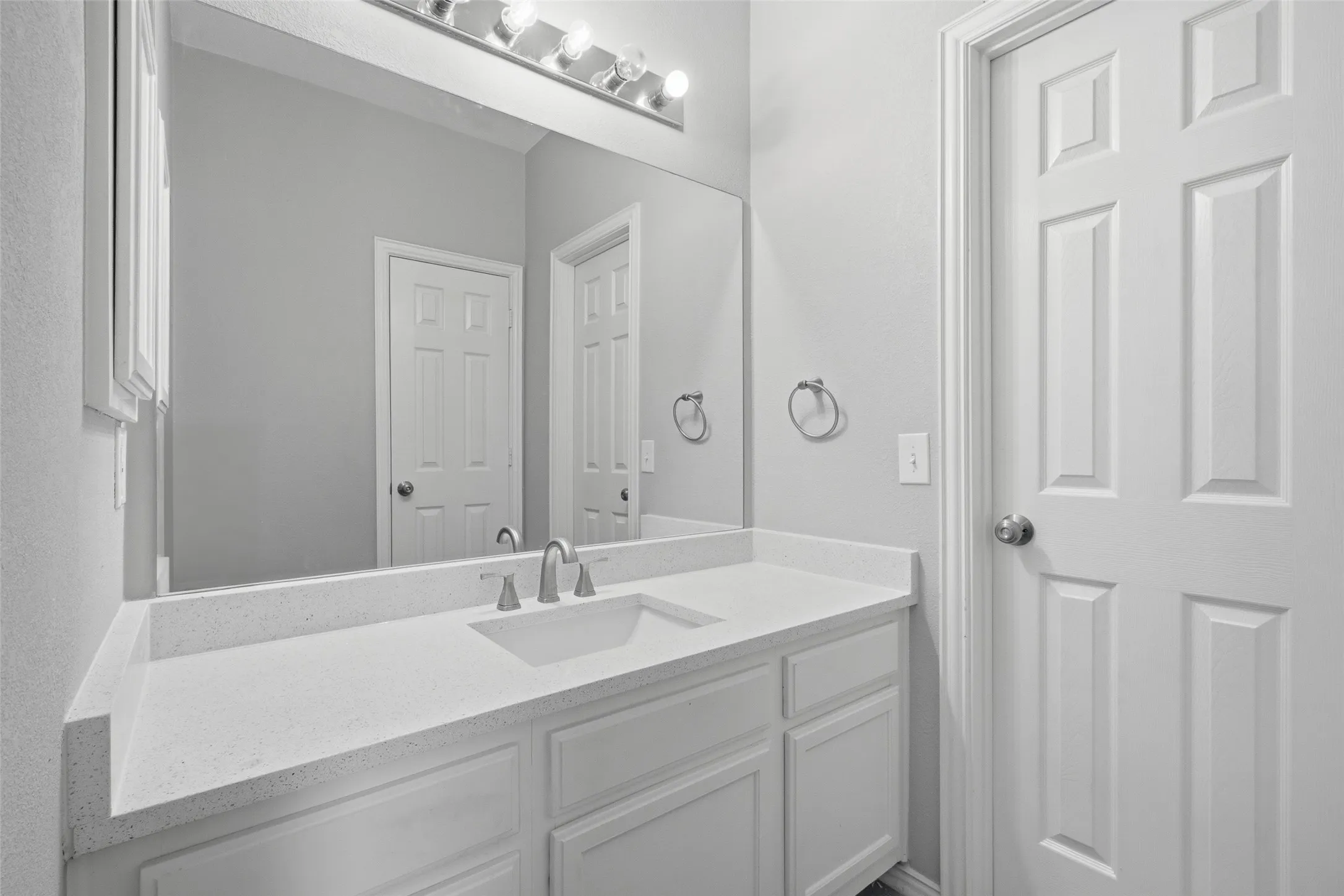Jack and Jill bathroom with updated with a white quartz countertop, undermount sink, brushed nickel fixtures, and a large vanity mirror with Hollywood-style lighting — this secondary bathroom punches above its weight. Clean, bright, and move-in ready.