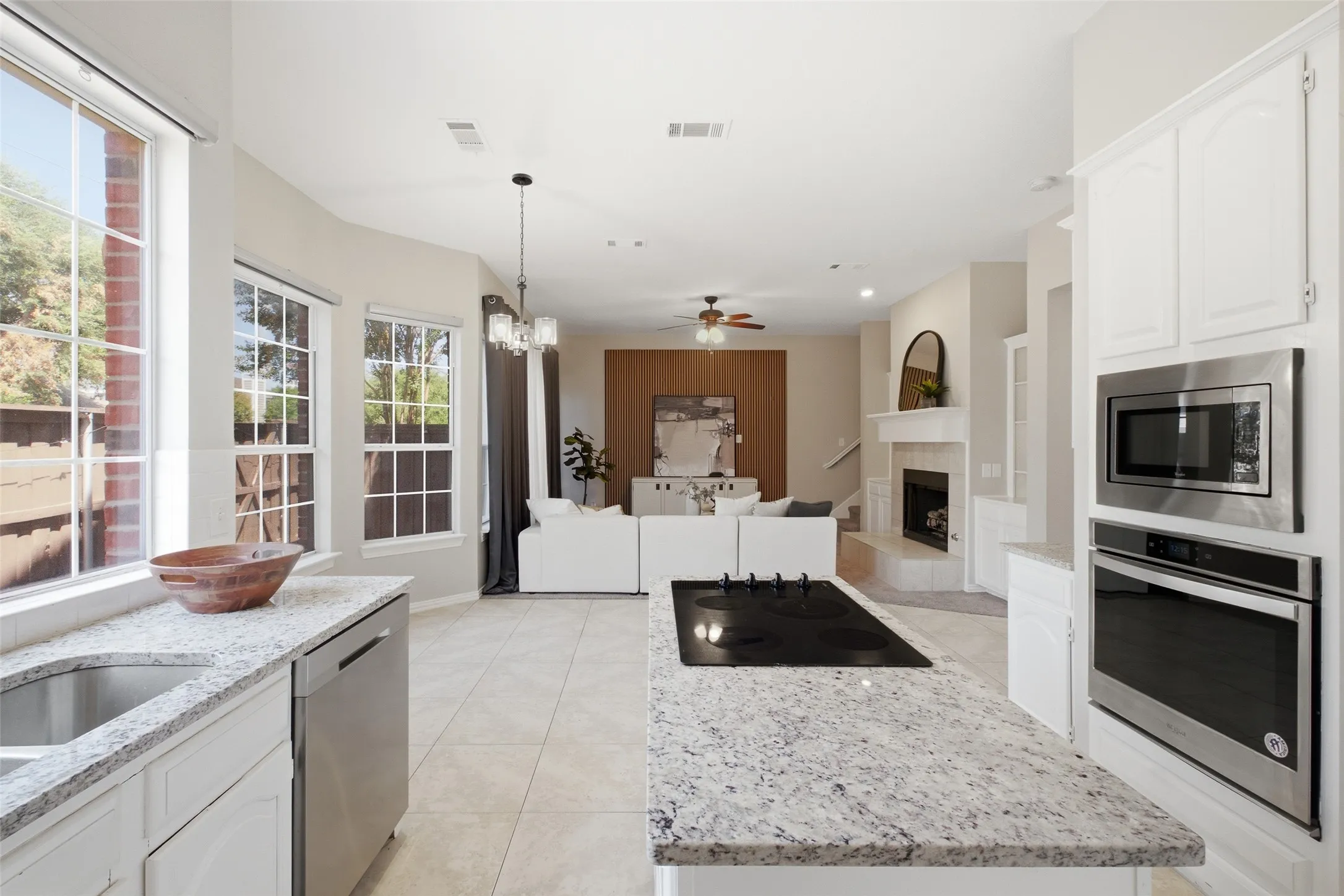 From the kitchen island, the sightline opens directly into the family room — a true open-concept layout that's perfect for entertaining. Abundant counter space, a granite island with cooktop, and a wall of windows keep the kitchen bright and connected to the main living area.
