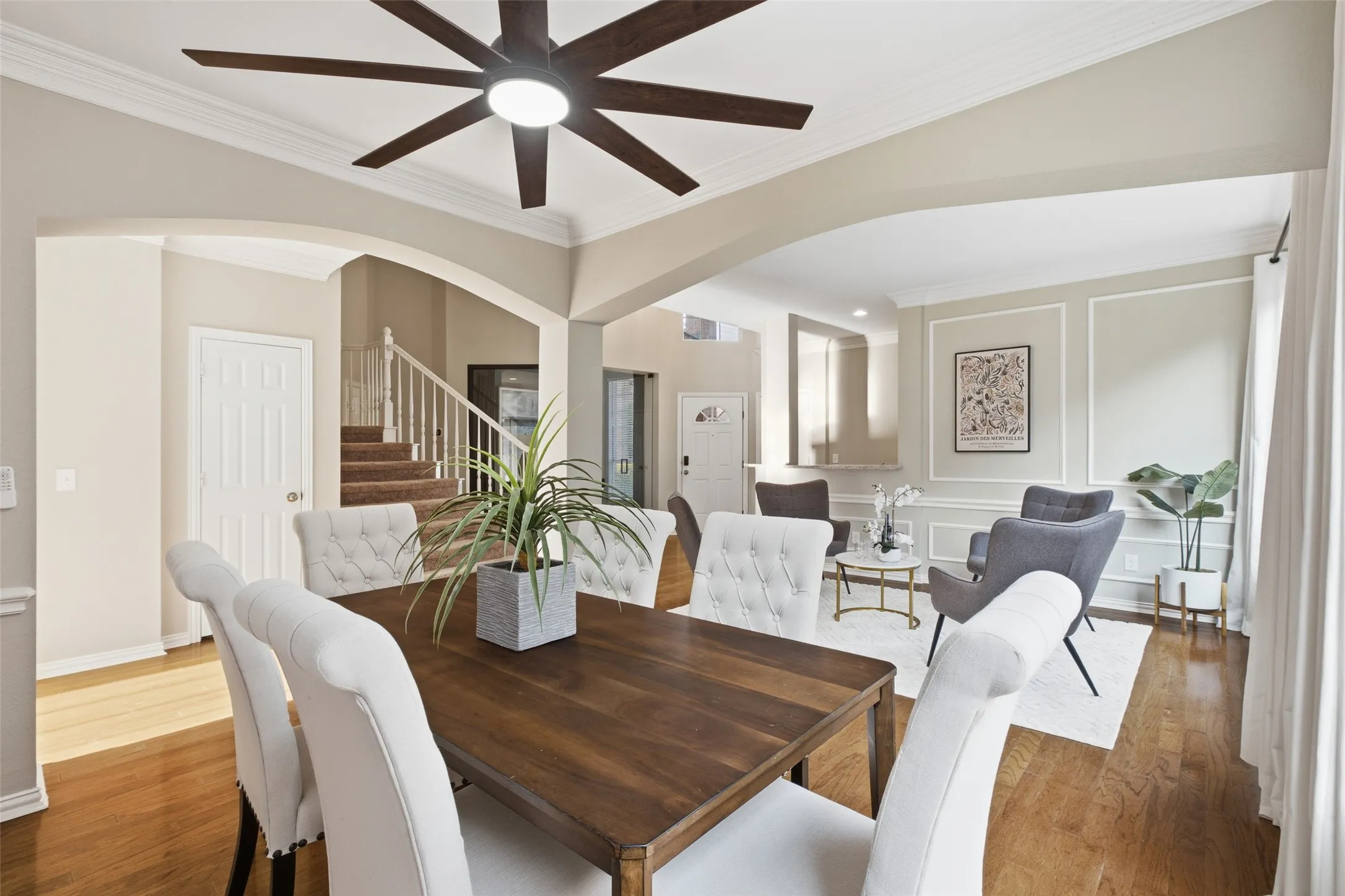 A generously sized formal dining room featuring crown molding, decorative wall trim, a statement ceiling fan, and elegant arched doorways connecting it to both the formal living room and the main hall. This space is made to host.

