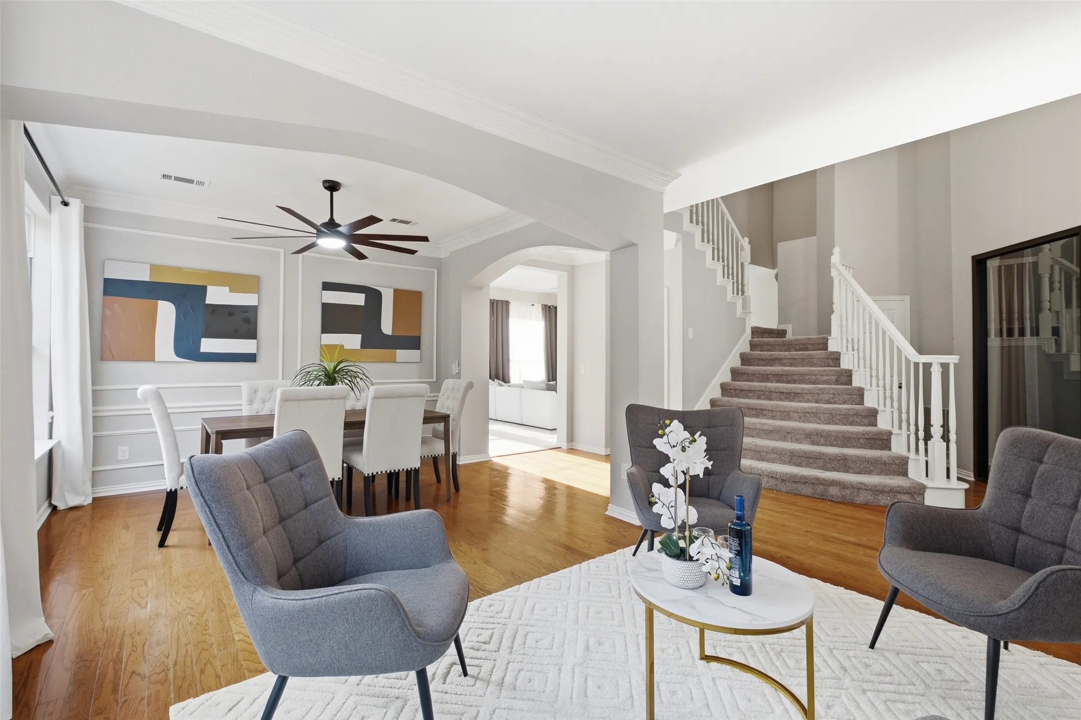 The formal living room's versatile layout is on full display, with a clear view through the arched opening into the formal dining room beyond. High ceilings, crown molding, and an abundance of natural light complete the picture.
