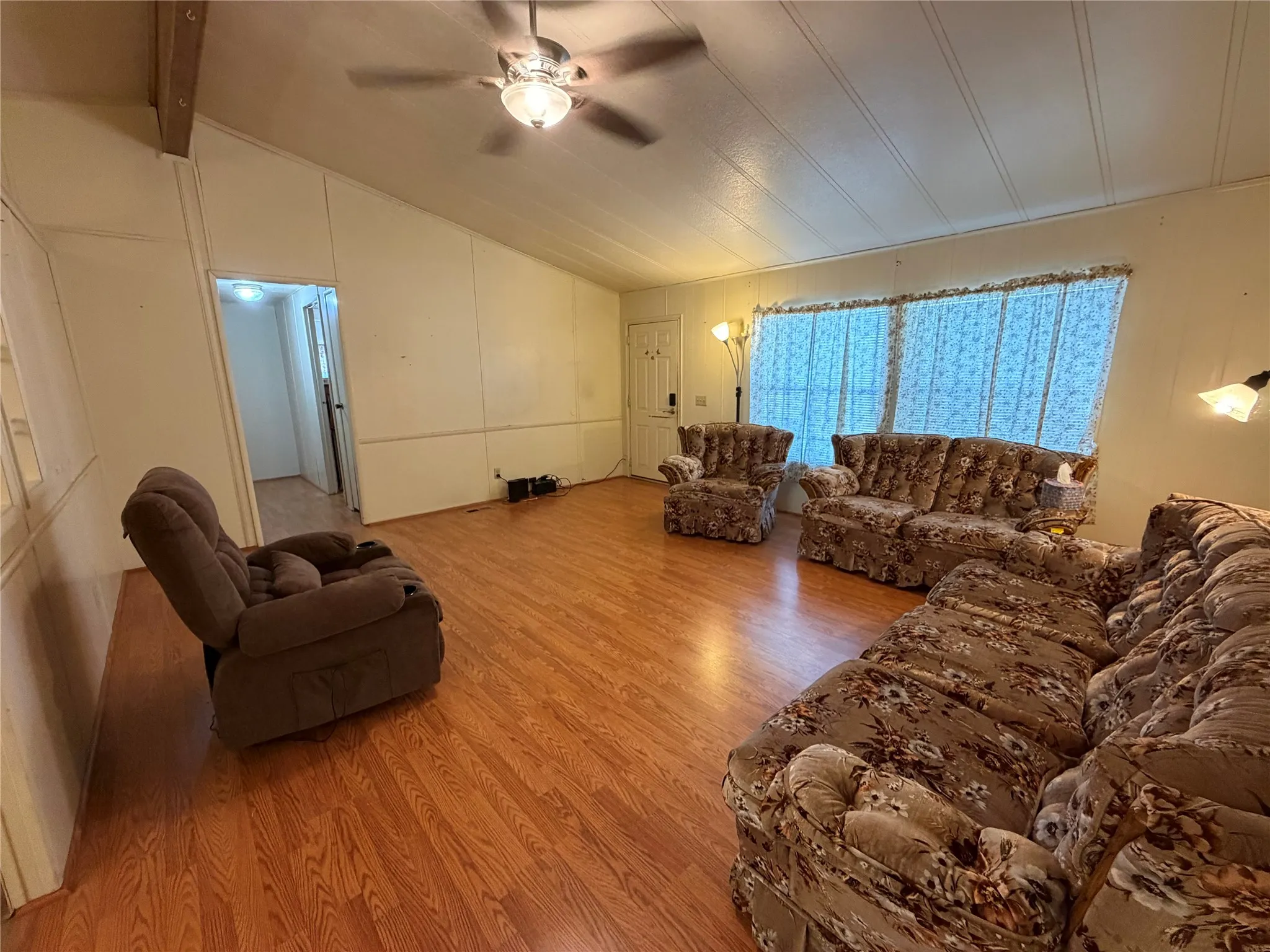 Wood-finish flooring with a ceiling fan light fixture and a sloped ceiling