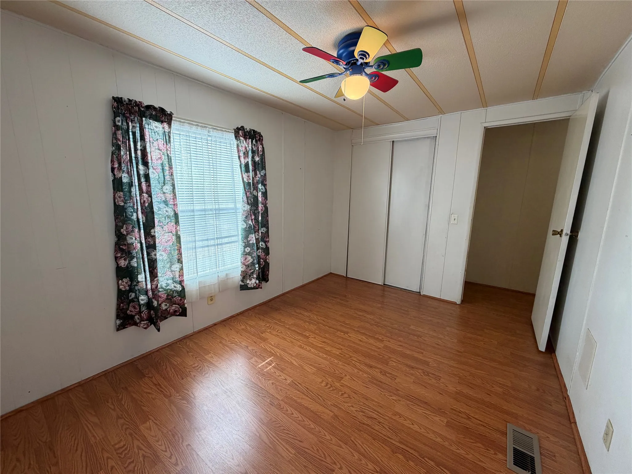 Wood-finish flooring, white walls, and a ceiling fan with integrated lighting