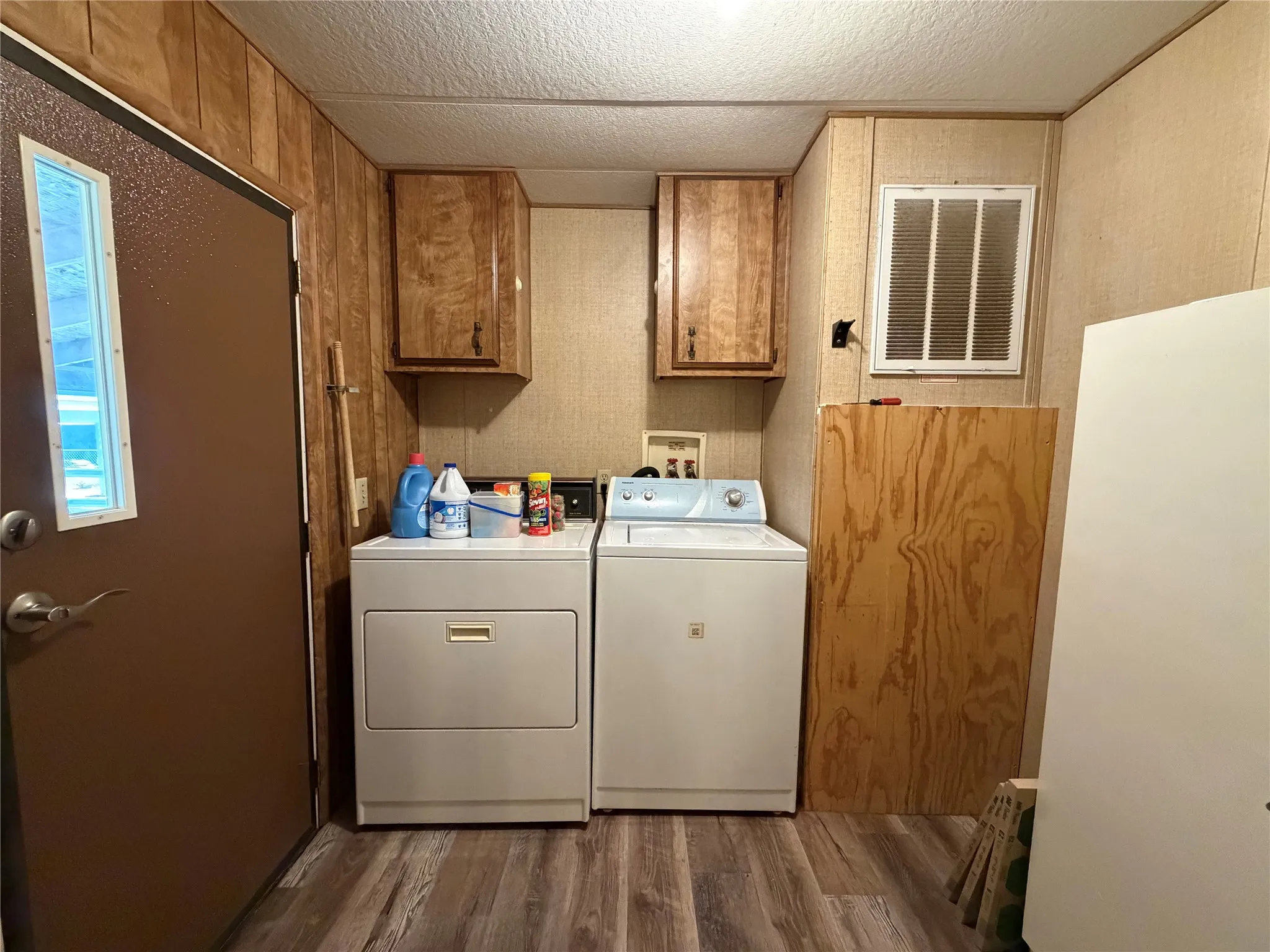 Wood-finish flooring with a utility door and two wall-mounted wood-finish cabinets