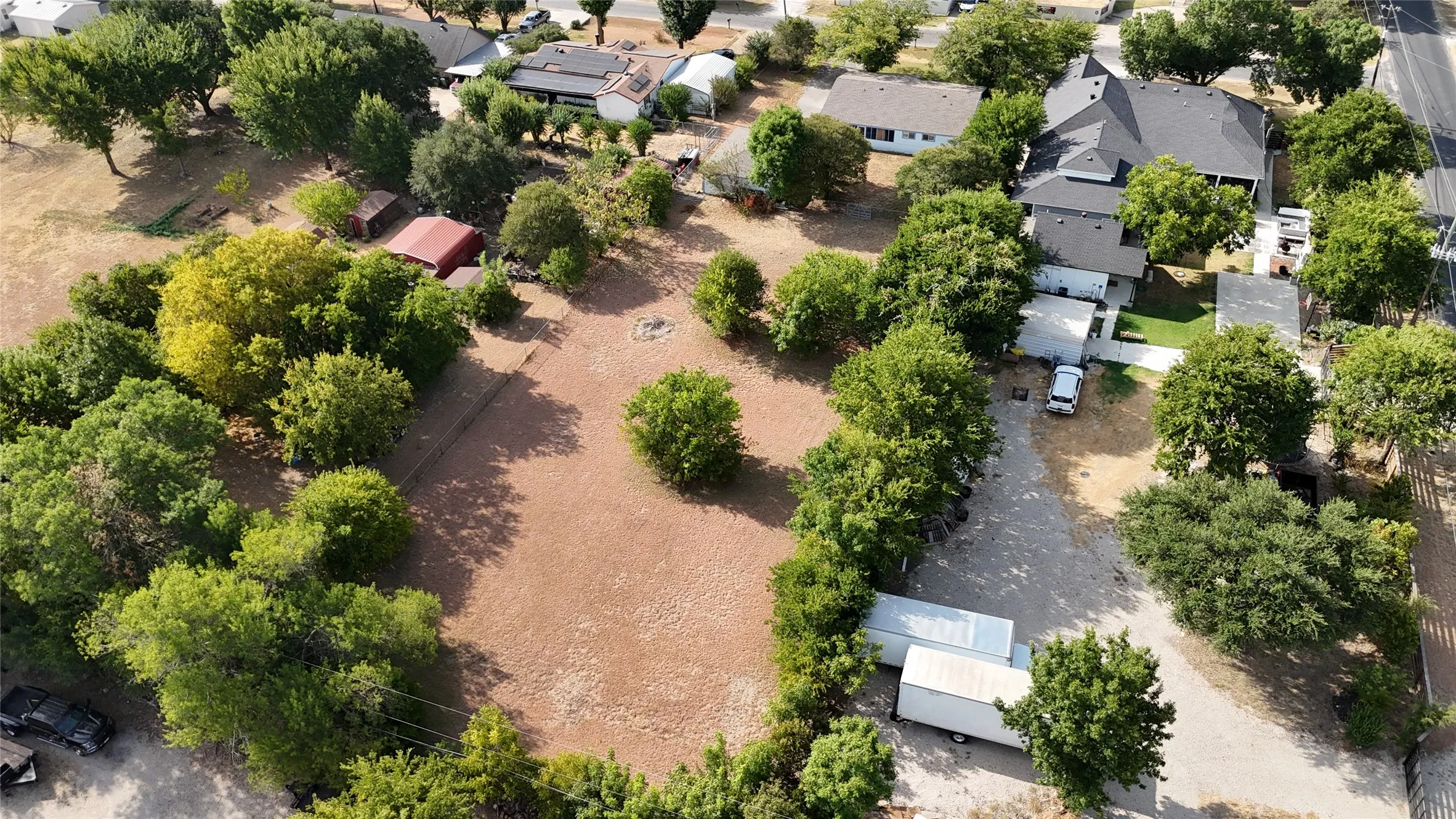 Expansive property featuring mature trees and open land, with a residential structure and outbuilding