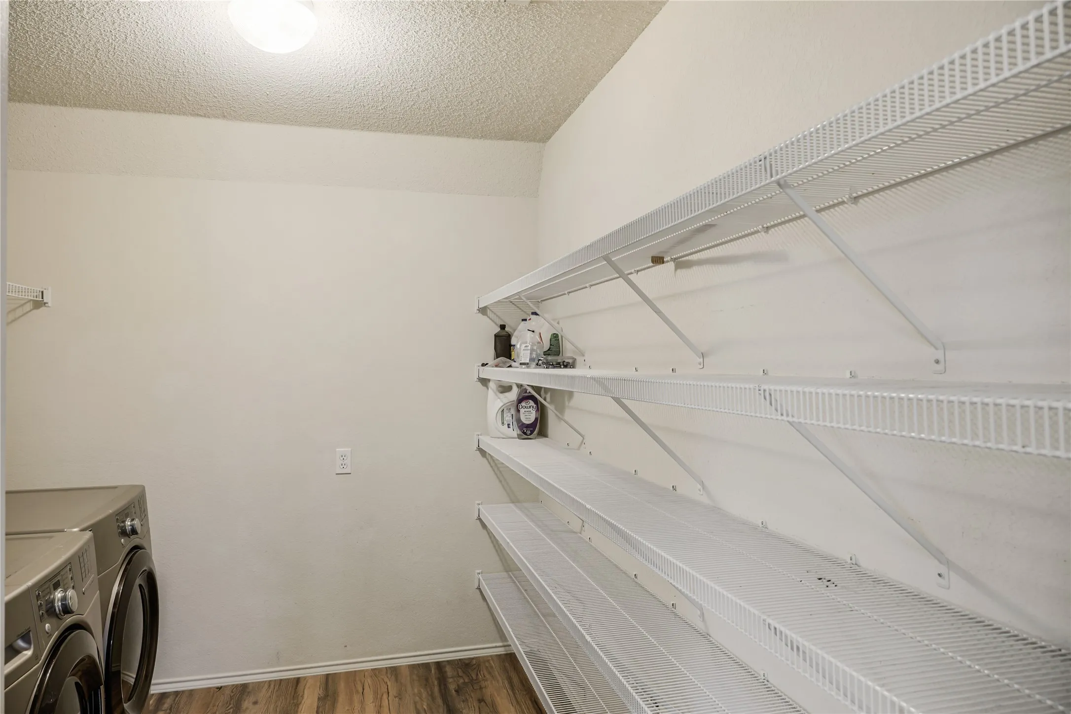 The large utility room features a full sized washer and dryer and a generous amount of shelving for pantry and storage.