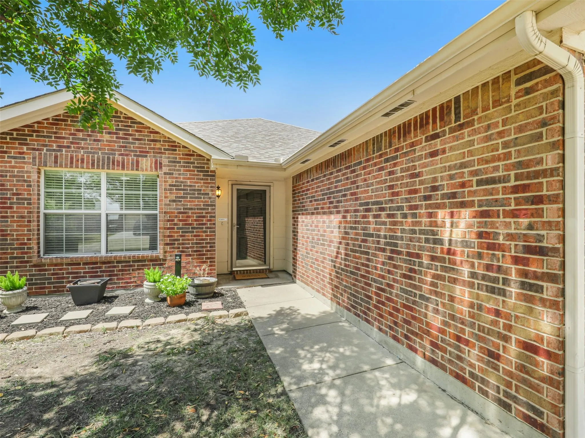 Brick home with gutters and a landscaped entry.
