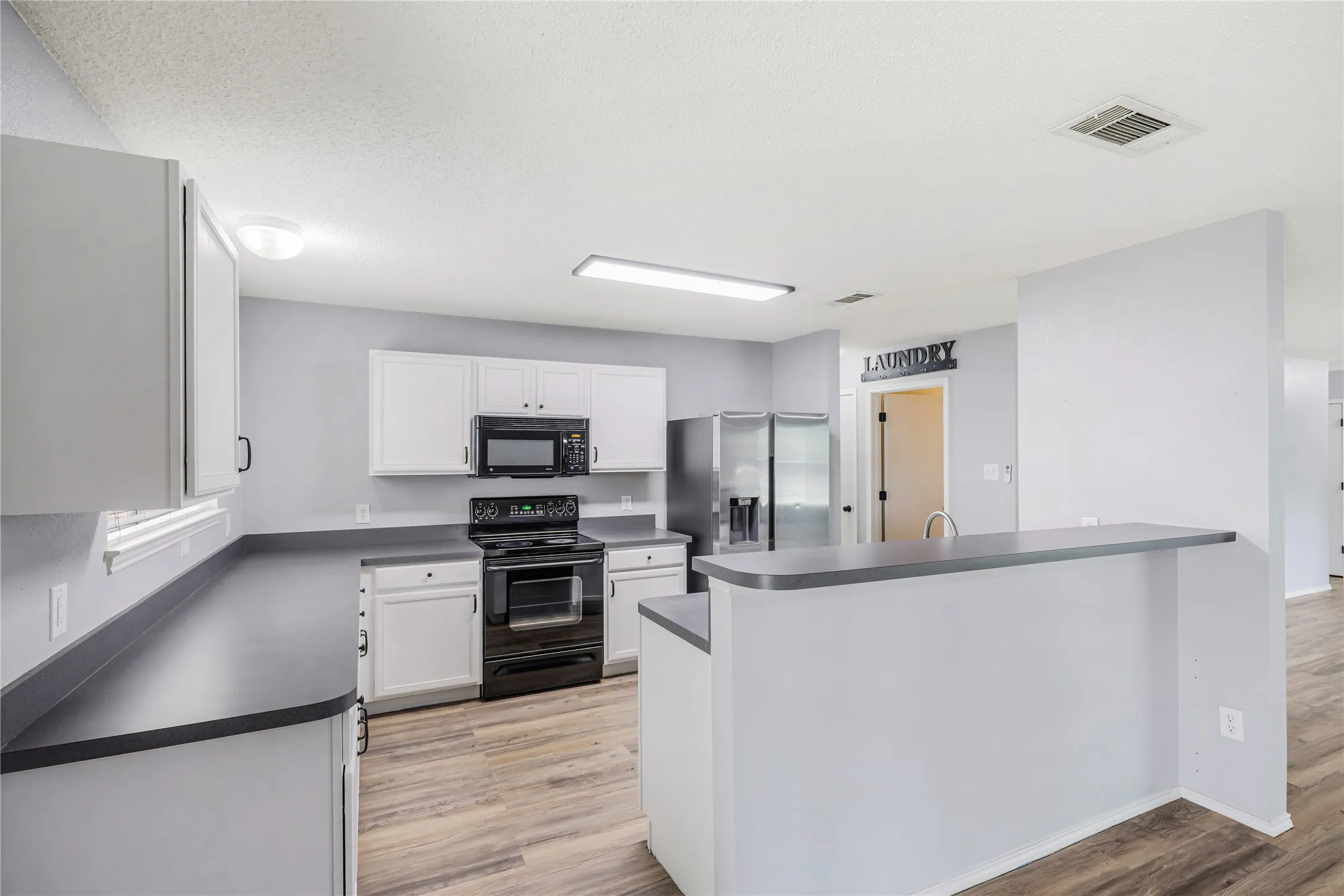 This view of the kitchen features the large breakfast bar and generous counter space.