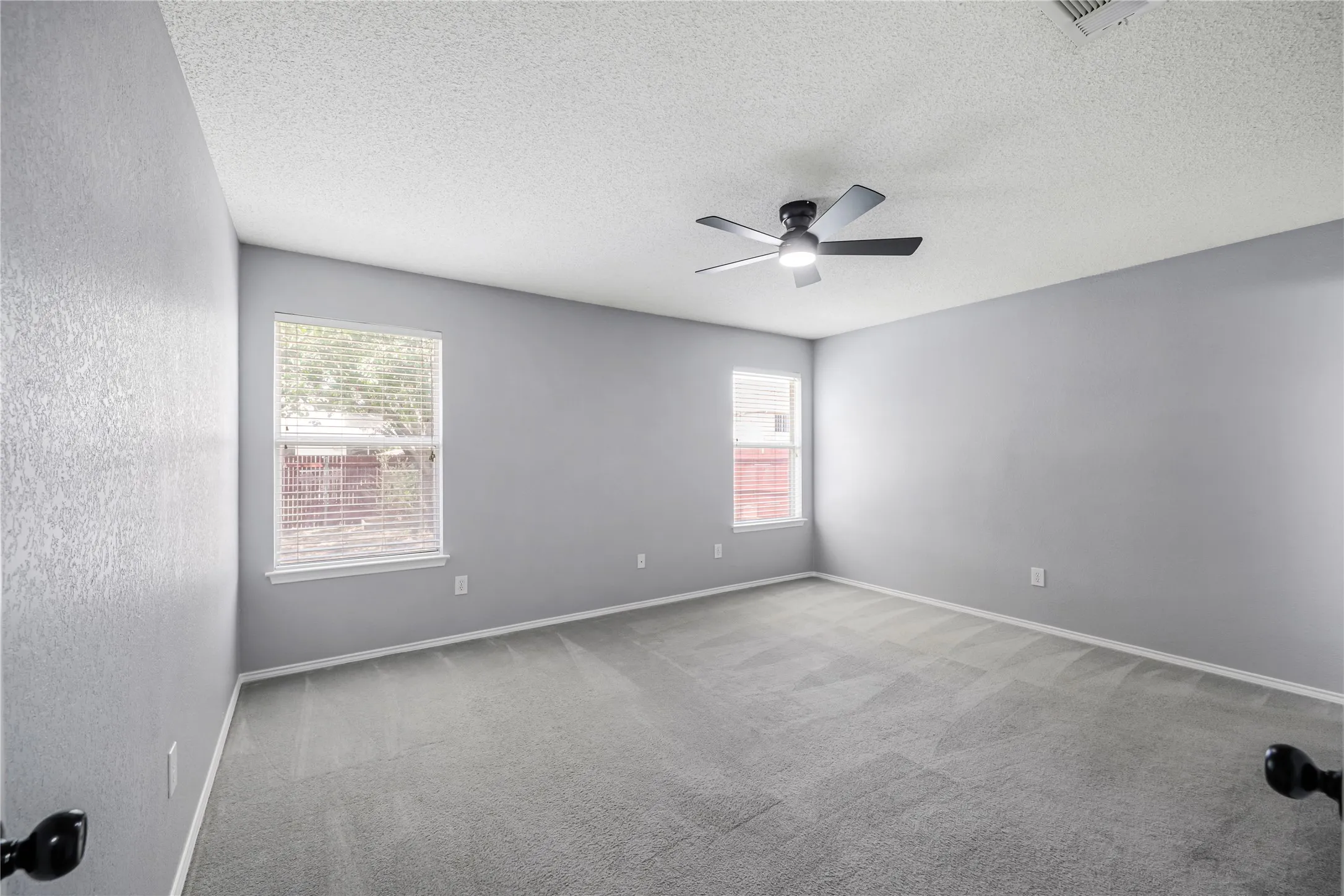This large primary bedroom looks on to the large backyard and features good wall space for furniture placement