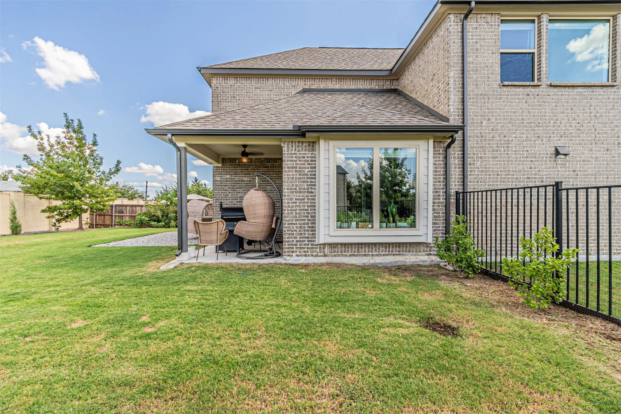 Brick exterior with a covered patio, featuring an outdoor ceiling fan and integrated lighting
