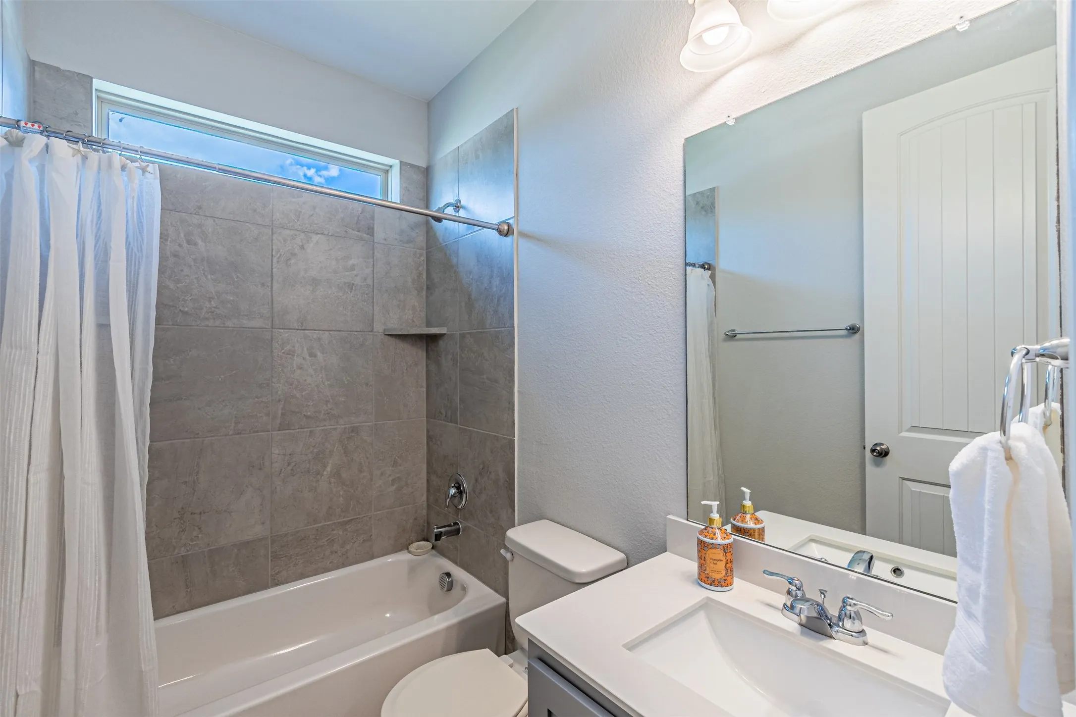 Bathroom featuring a combination bathtub and shower, tiled shower surround with an integrated niche, a vanity with an integrated sink, and a wall-mounted mirror