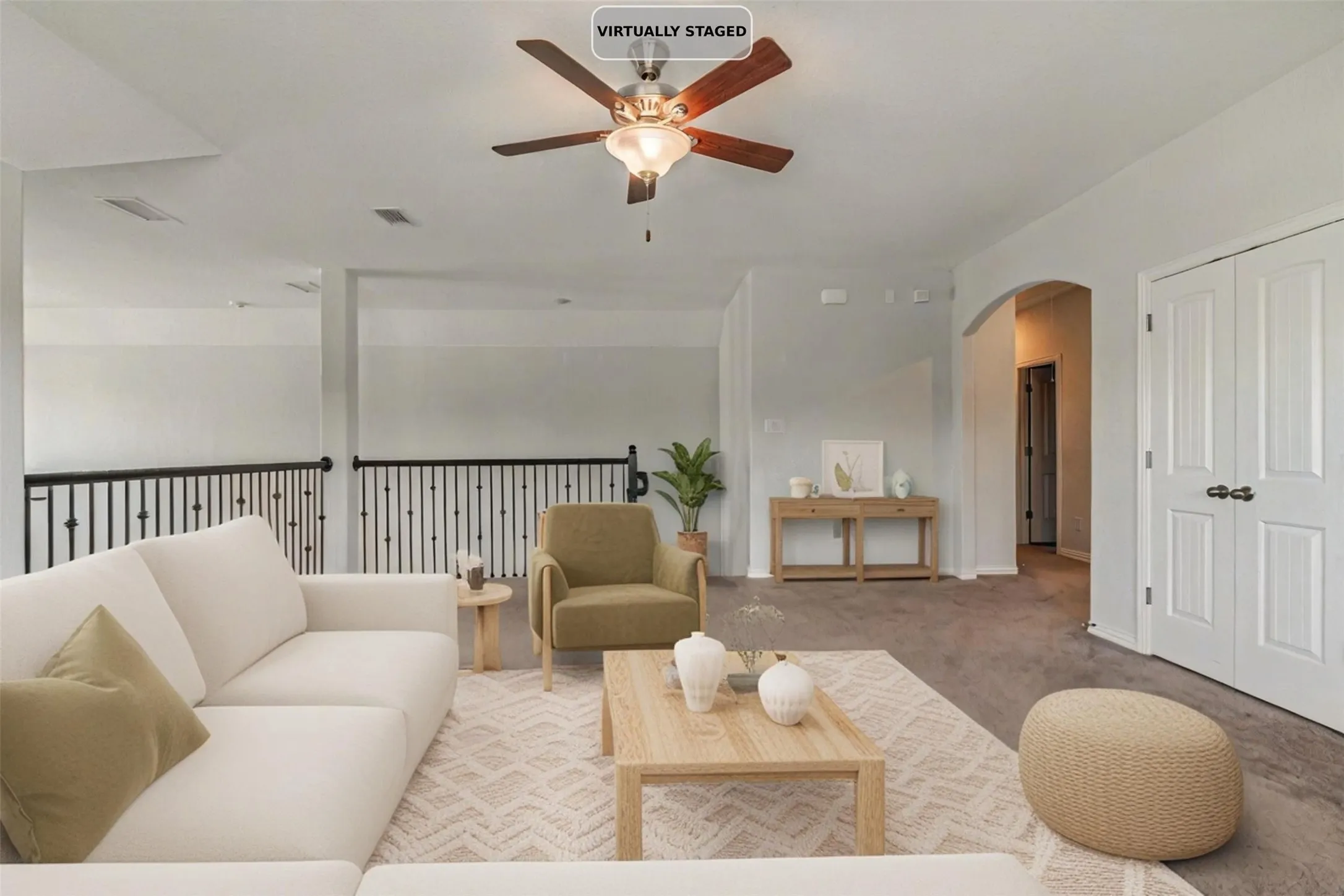 Carpeted living area with a ceiling fan, arched doorway, and white paneled double doors