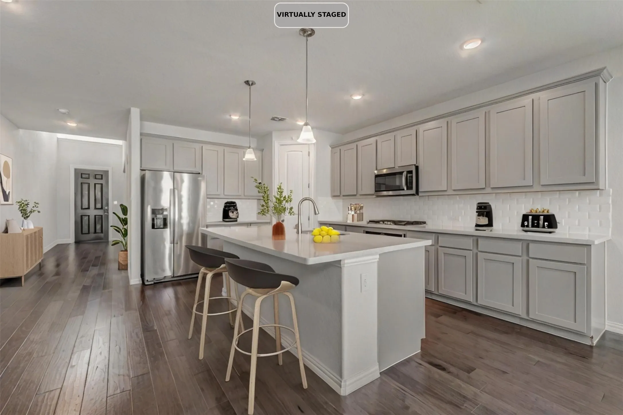 Kitchen featuring an island with built-in seating, stainless steel appliances, light gray cabinetry, white countertops, and wood-finish flooring