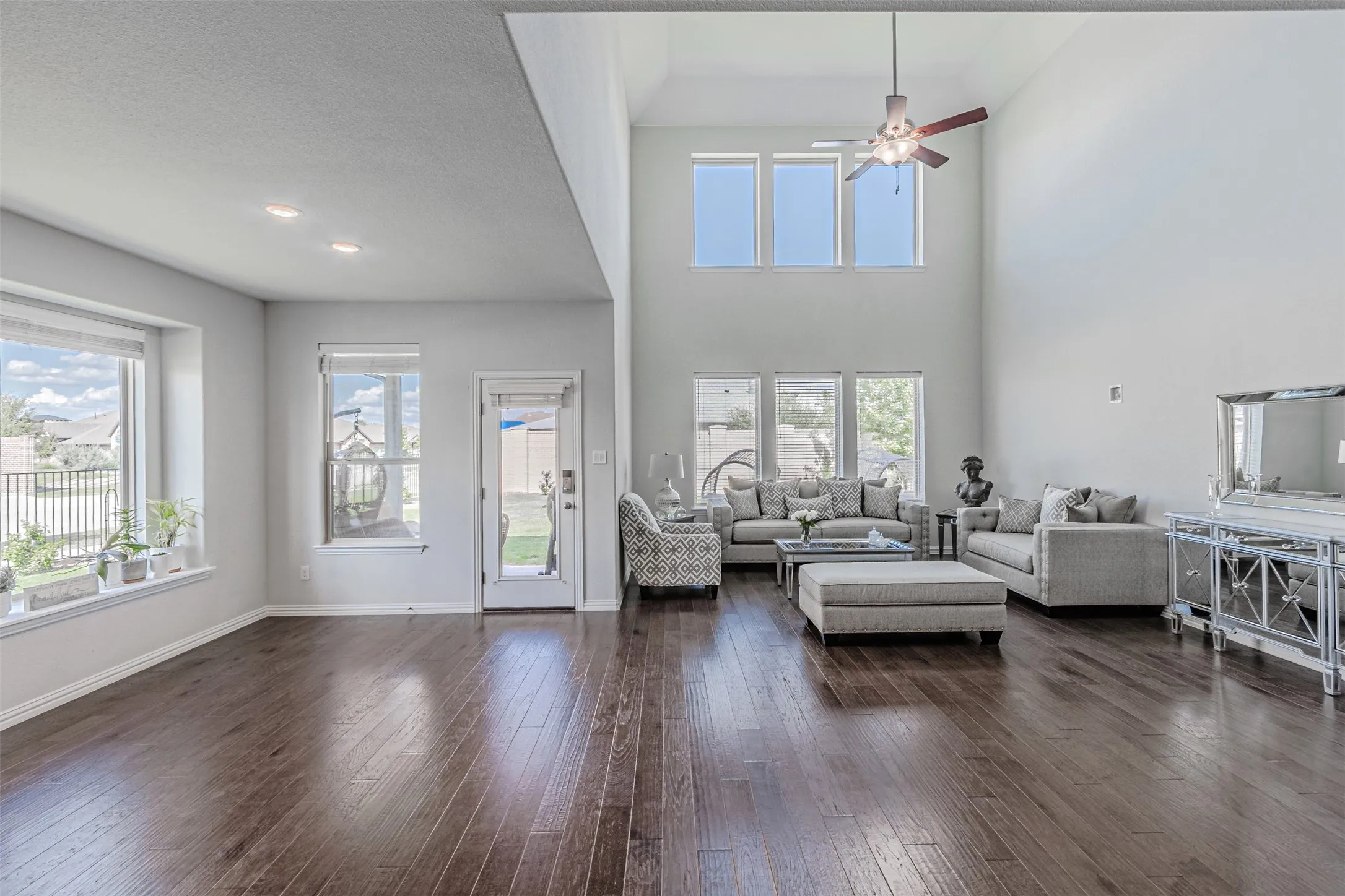 Vaulted ceilings with an upper window arrangement, wood-finish flooring, recessed lighting, and multiple windows