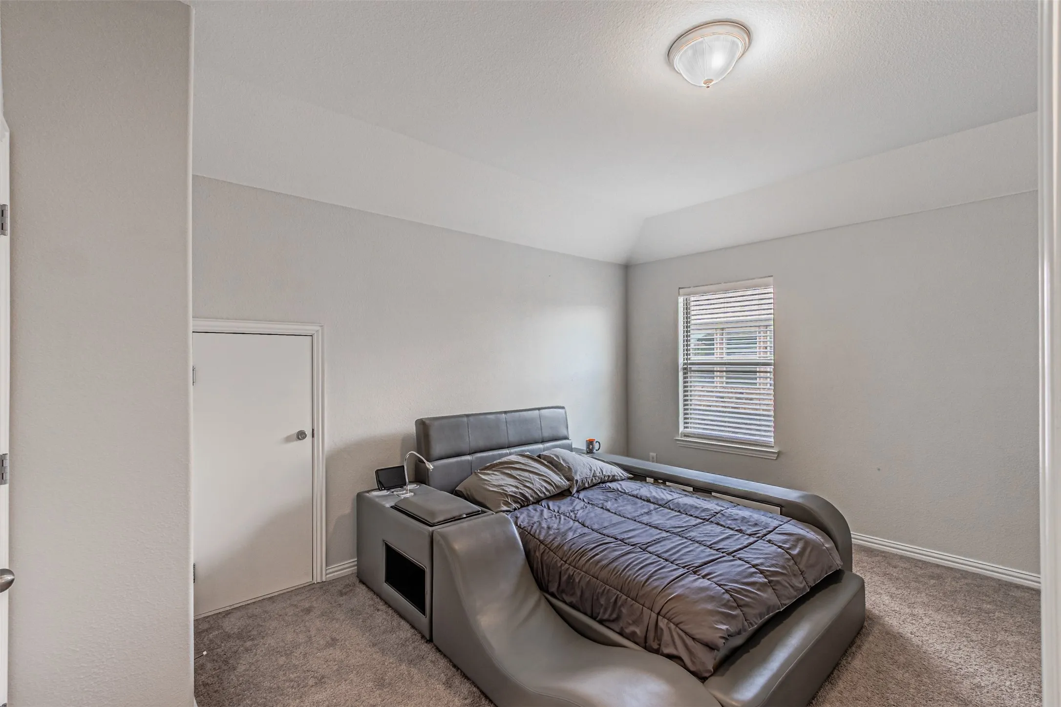 Carpeted flooring, vaulted ceiling, and a window with blinds