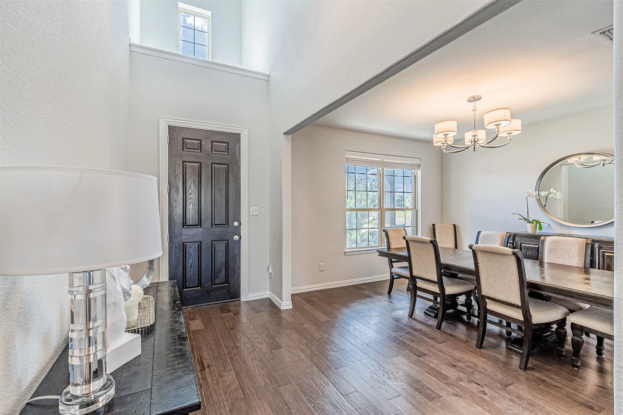 Wood-finish flooring, high ceilings, upper-level window, and a chandelier lighting fixture
