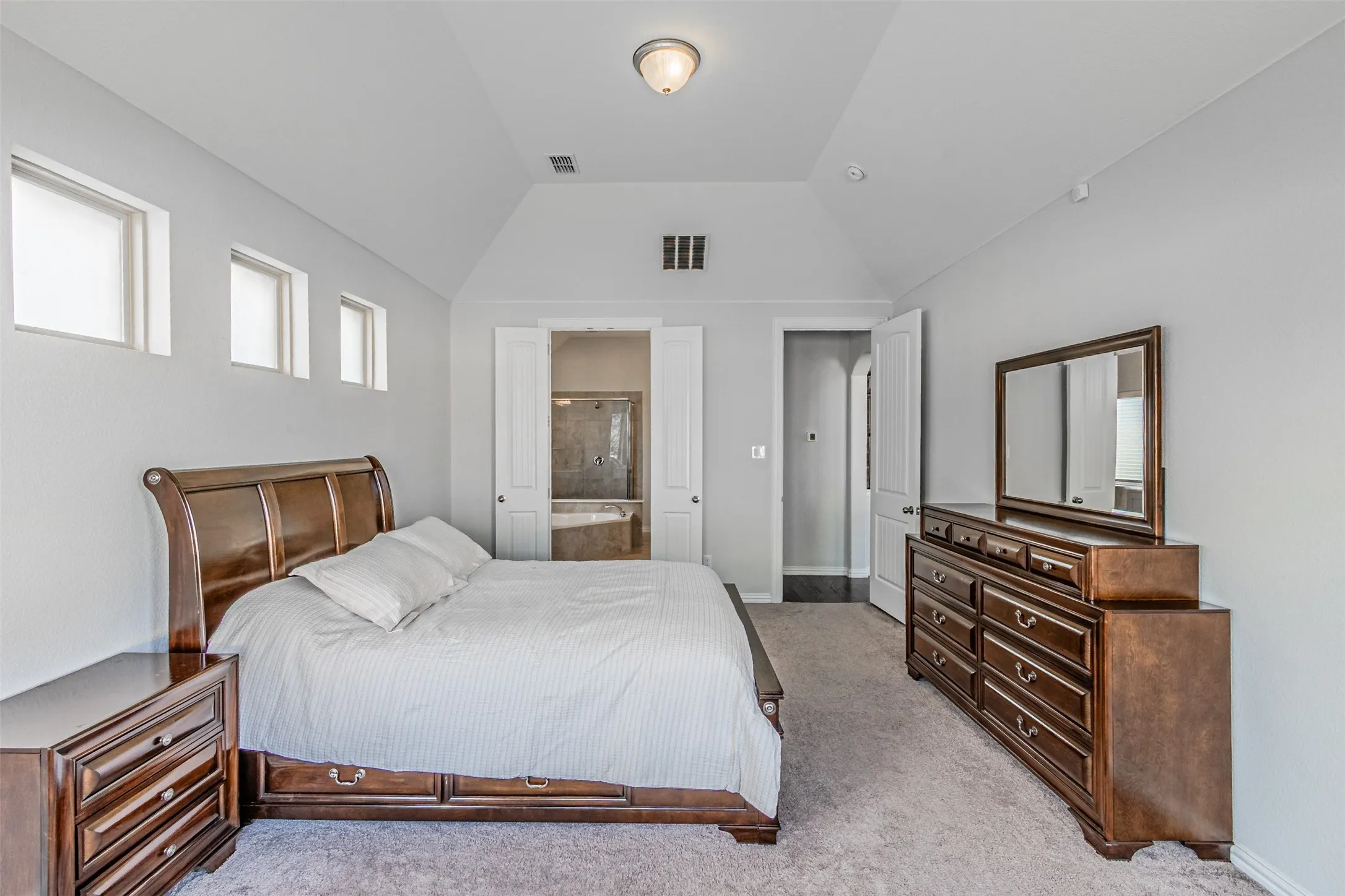 Vaulted ceiling, three transom windows, carpeted flooring, and a built-in ceiling light fixture