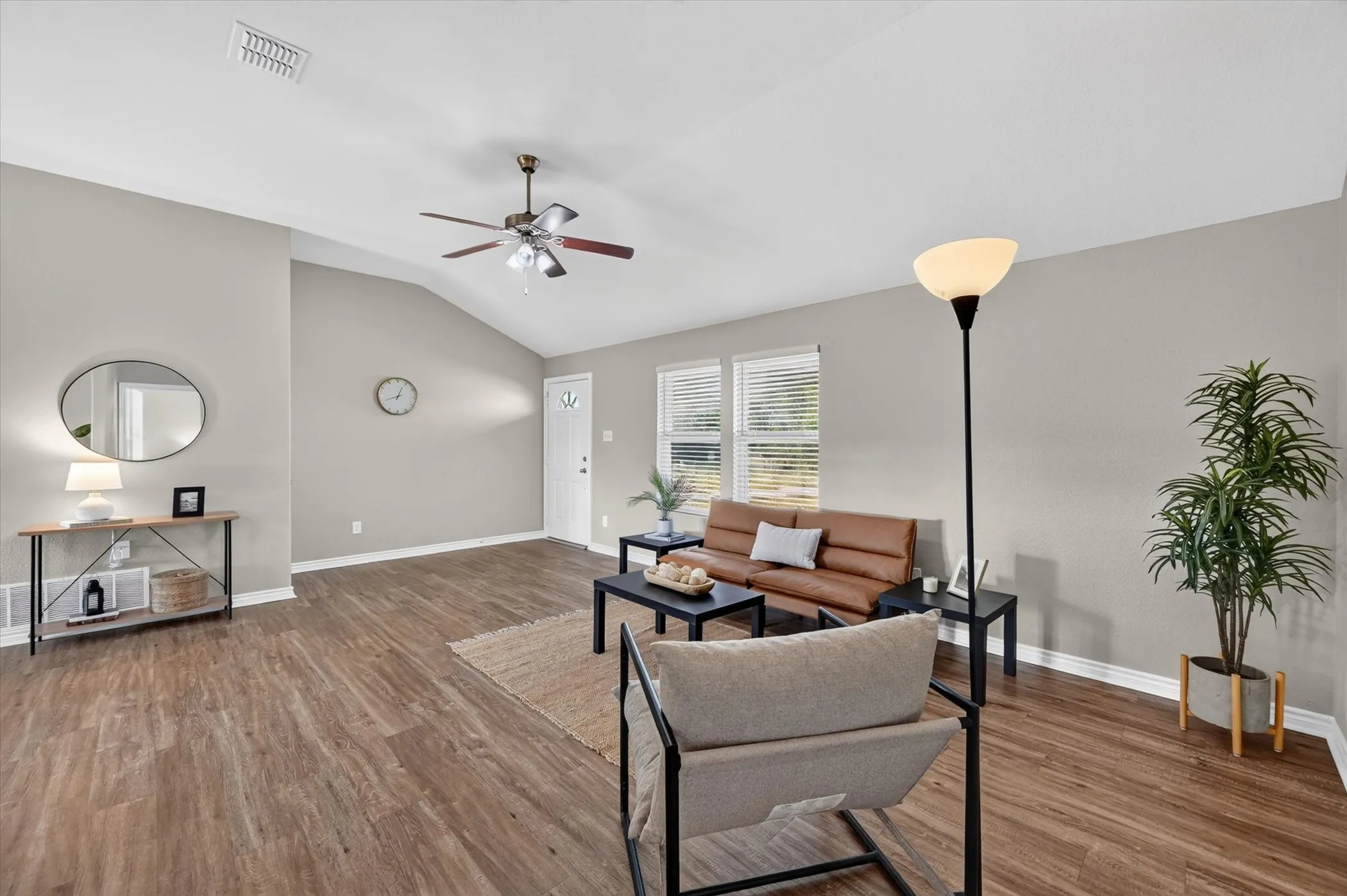 Vaulted ceiling with a ceiling fan, wood-finish flooring, white trim, and multiple windows with blinds
