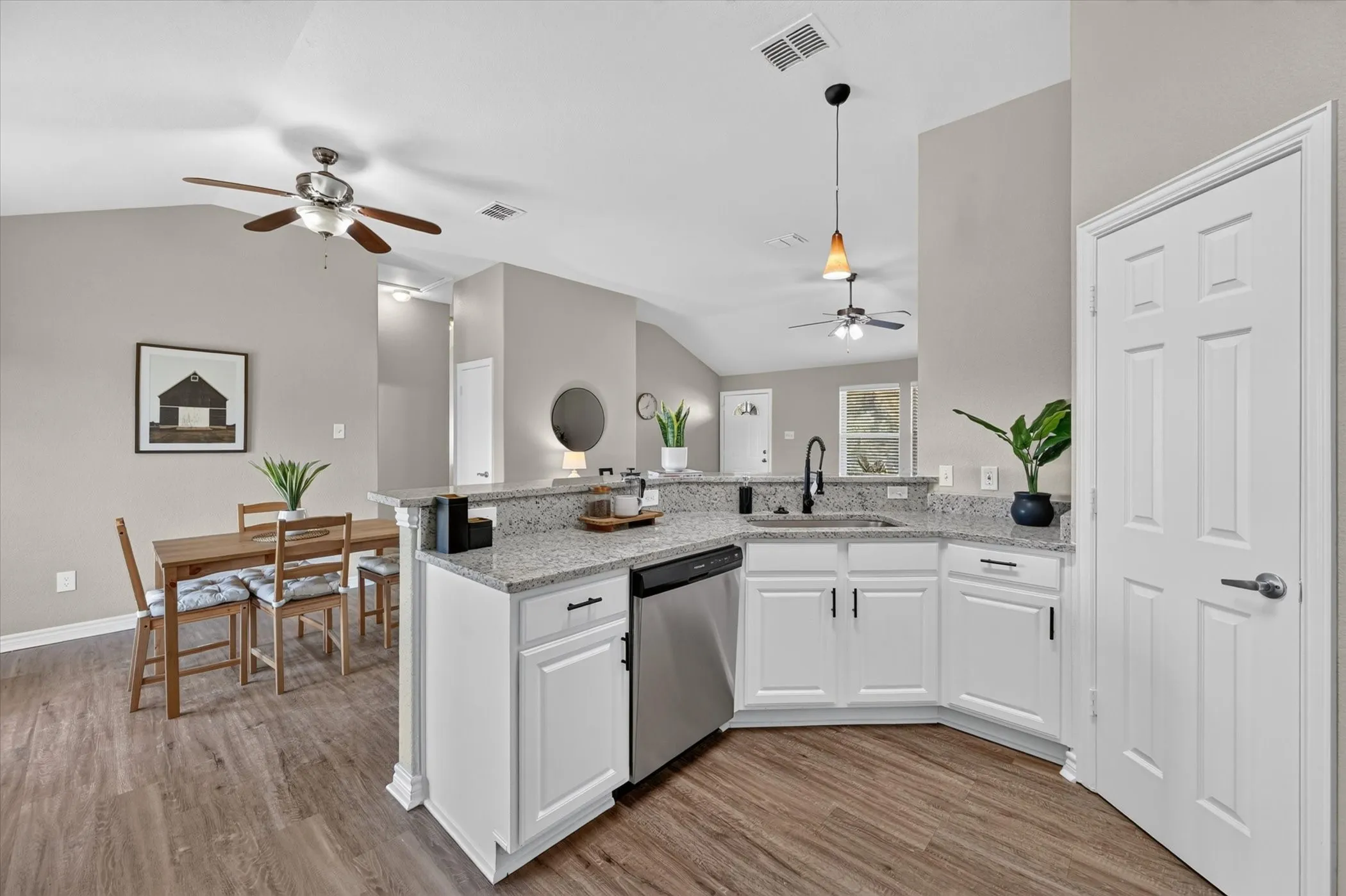 Well-appointed kitchen featuring white cabinetry, light-toned granite countertops, stainless steel appliances, and a stainless steel sink with a dark-finish faucet