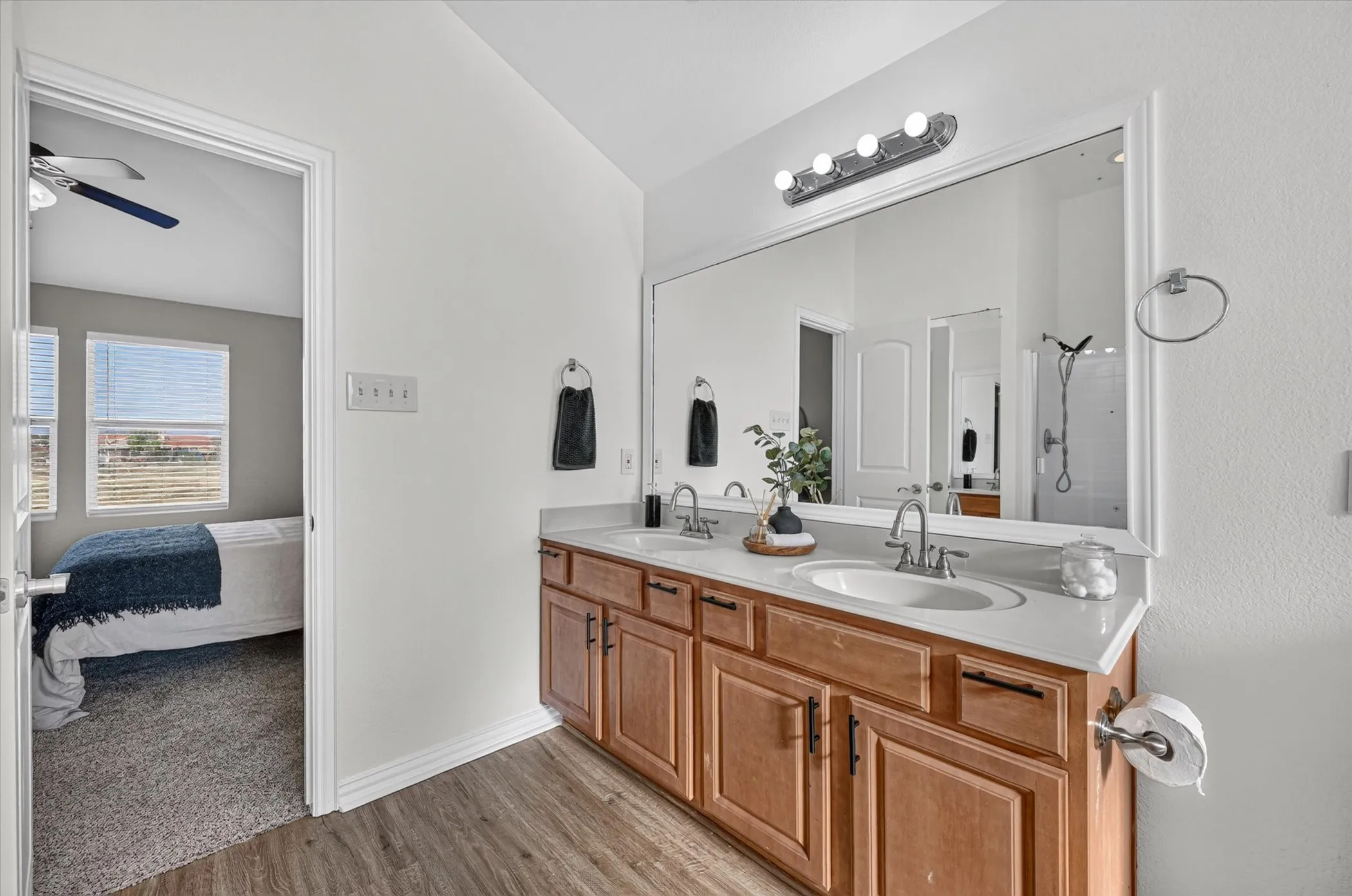 Dual vanity with undermount sinks, wood-finish cabinetry, and a large wall-mounted mirror