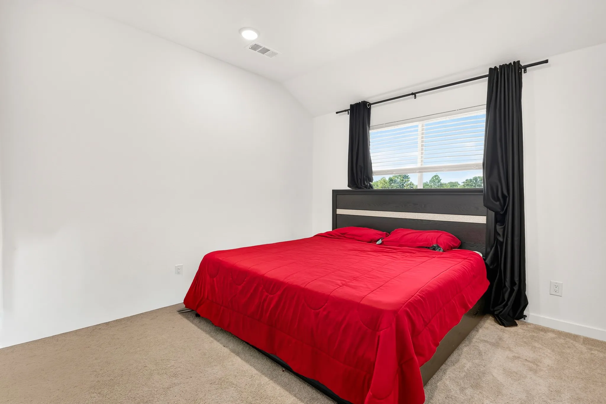 Recessed ceiling lighting, vaulted ceiling, neutral tone carpet, and a window with blinds