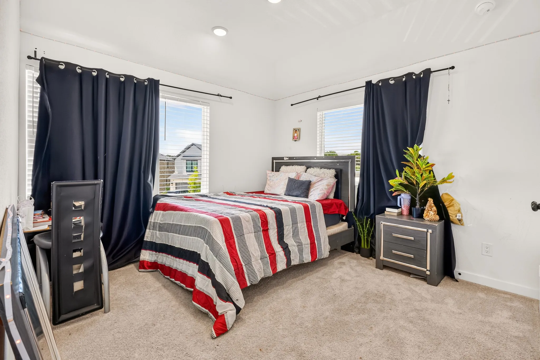Recessed lighting illuminates a carpeted interior with two windows featuring integrated blinds