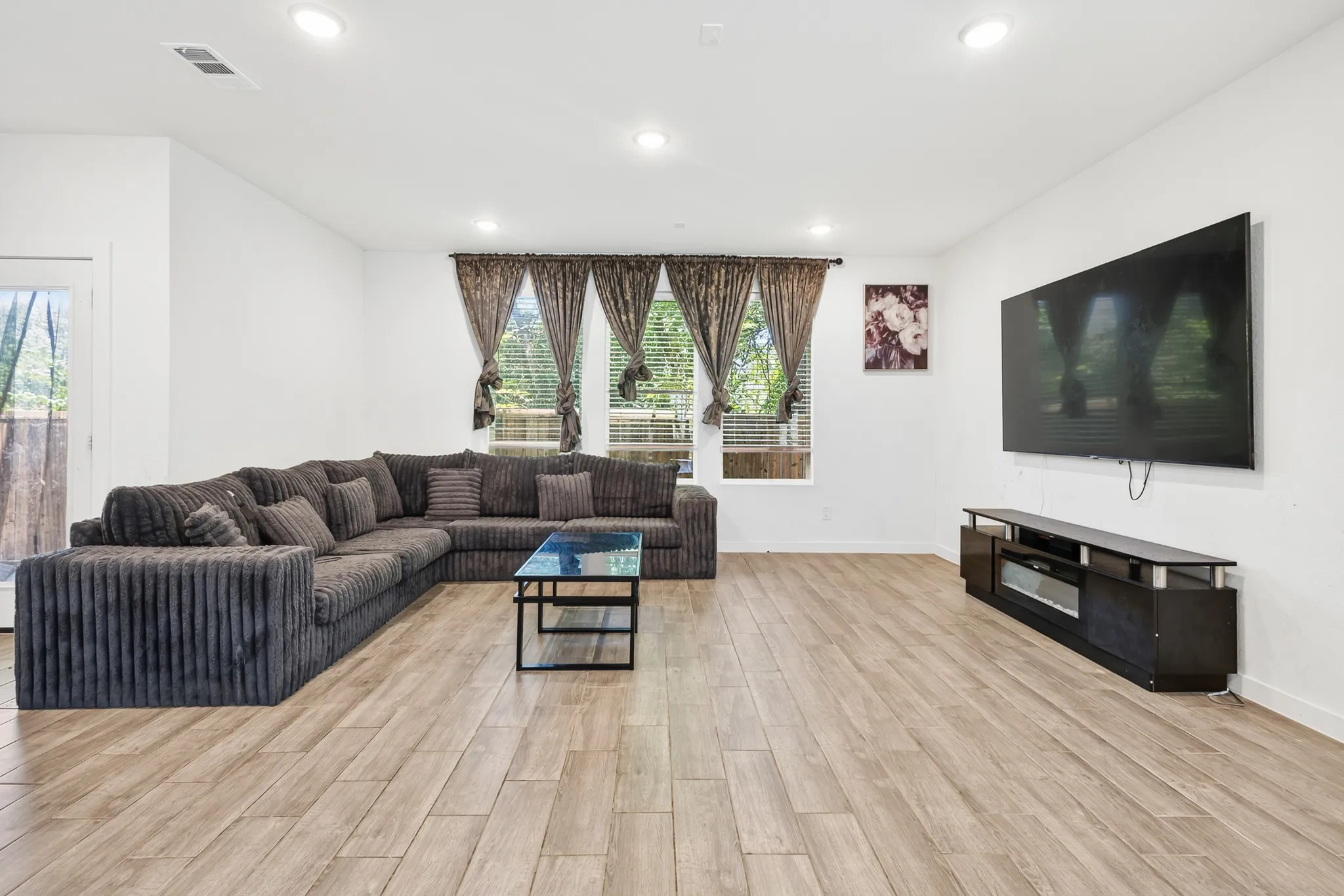 Wood-finish flooring throughout, recessed lighting, and multiple windows with blinds