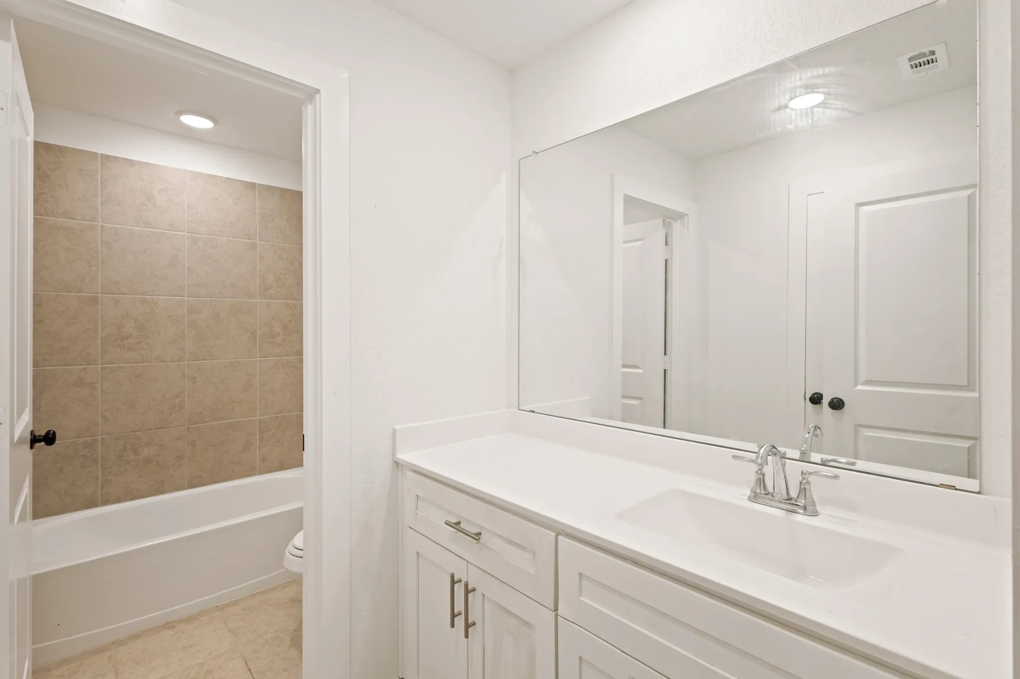 Bathroom with white vanity, integrated sink, and chrome faucet