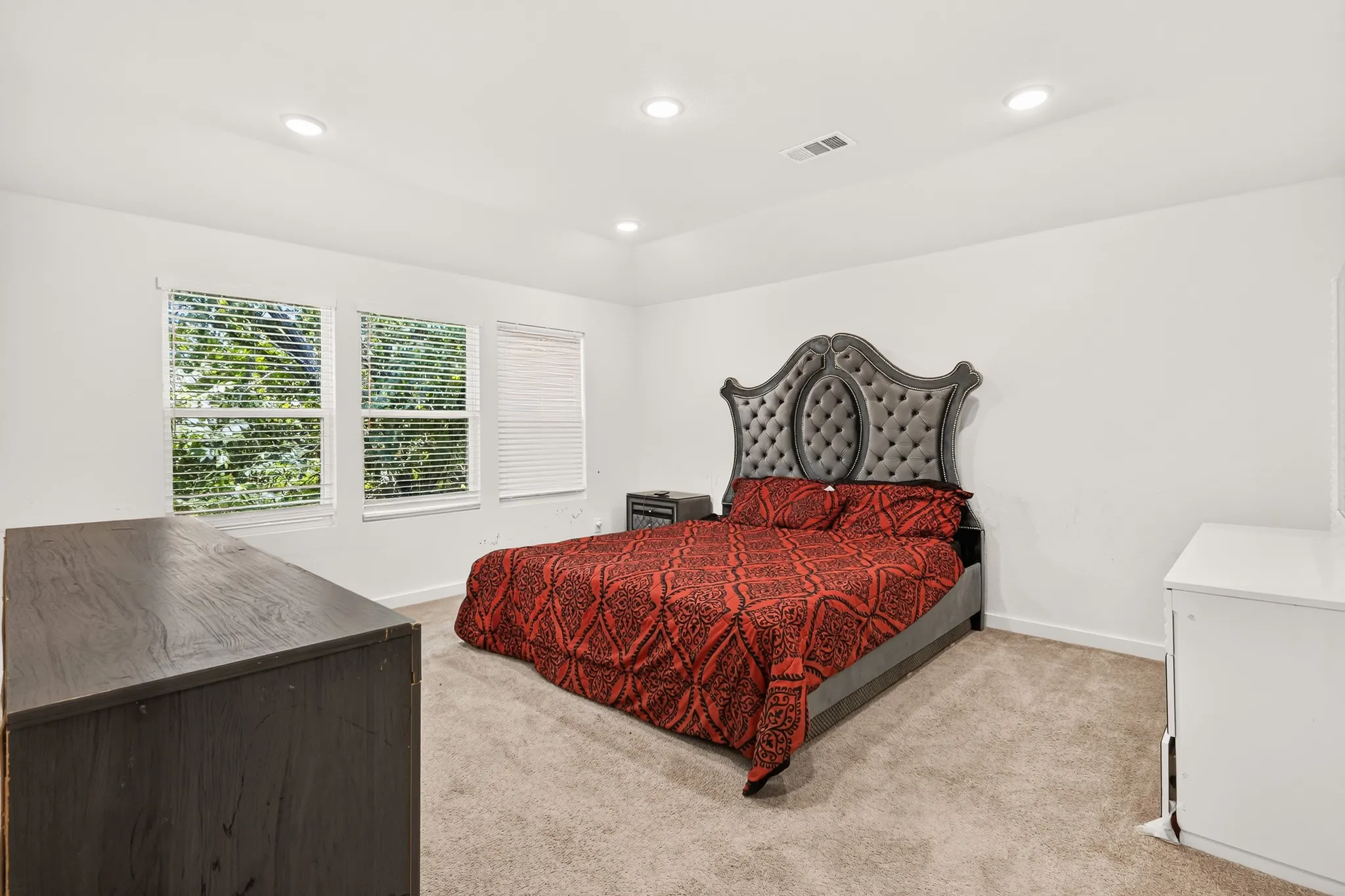 Recessed ceiling lighting, three windows with horizontal blinds, carpeted flooring, and white painted walls