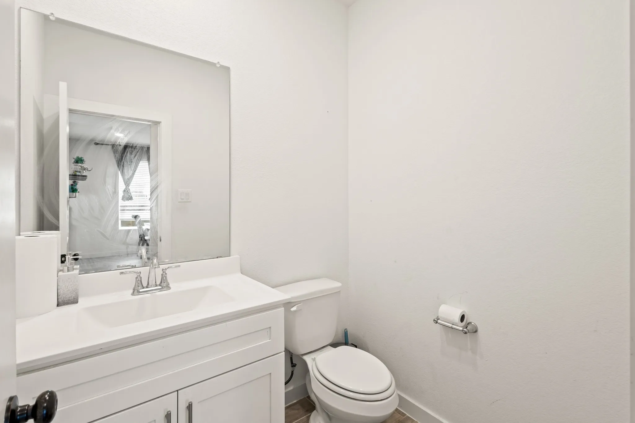 White vanity with a built-in sink, chrome faucet, and a large wall-mounted mirror
