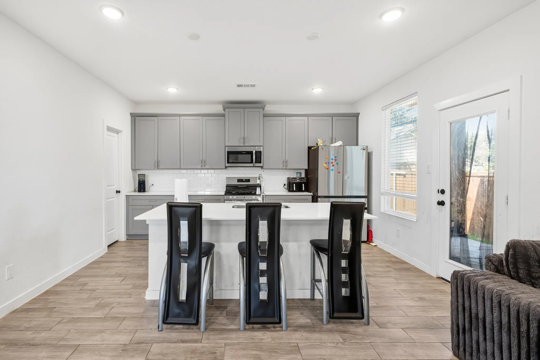 Kitchen featuring wood-finish flooring, recessed lighting, white subway tile backsplash, and gray cabinetry