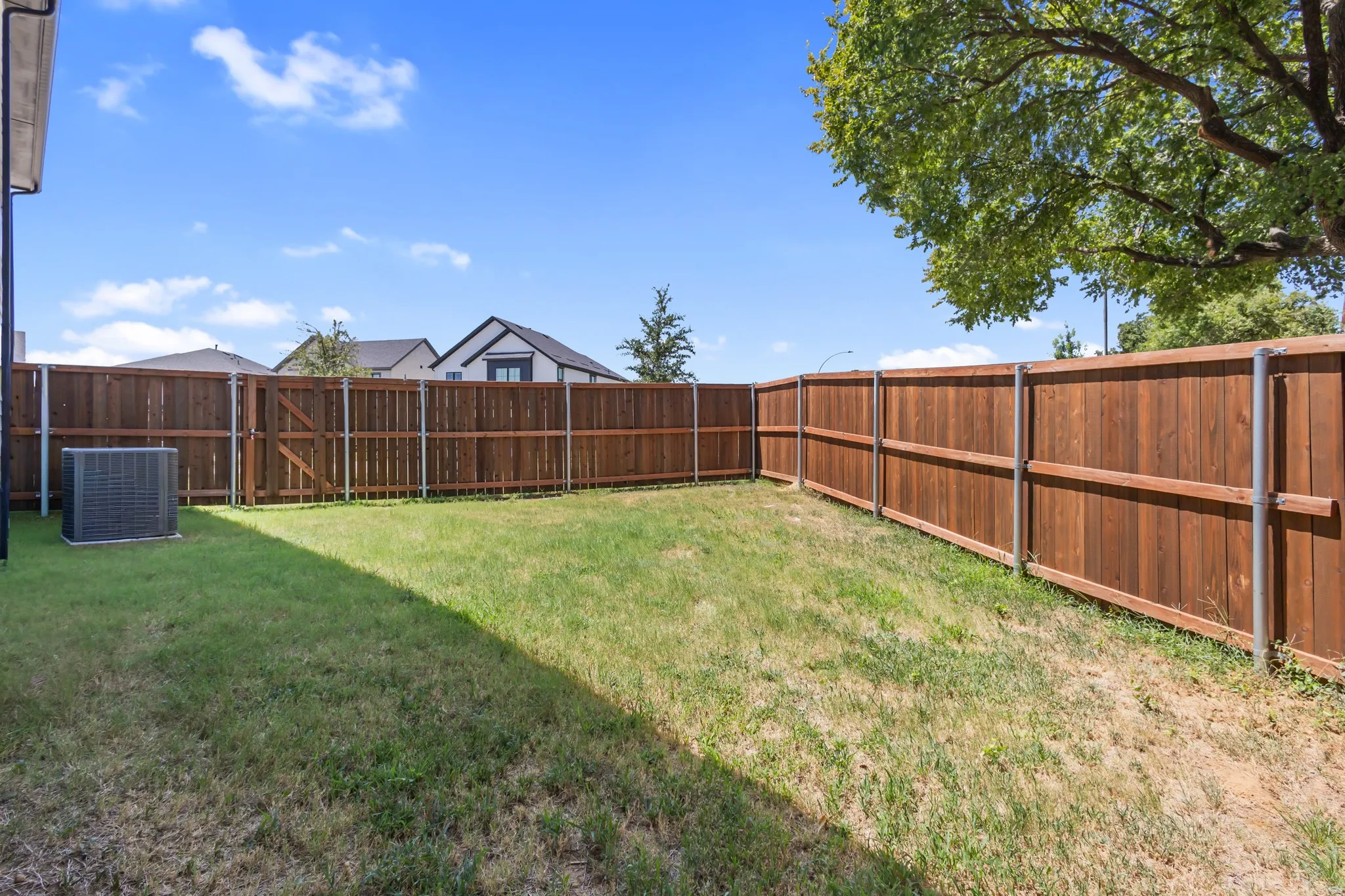 Expansive grassy yard with a full privacy fence featuring wood panels and metal posts