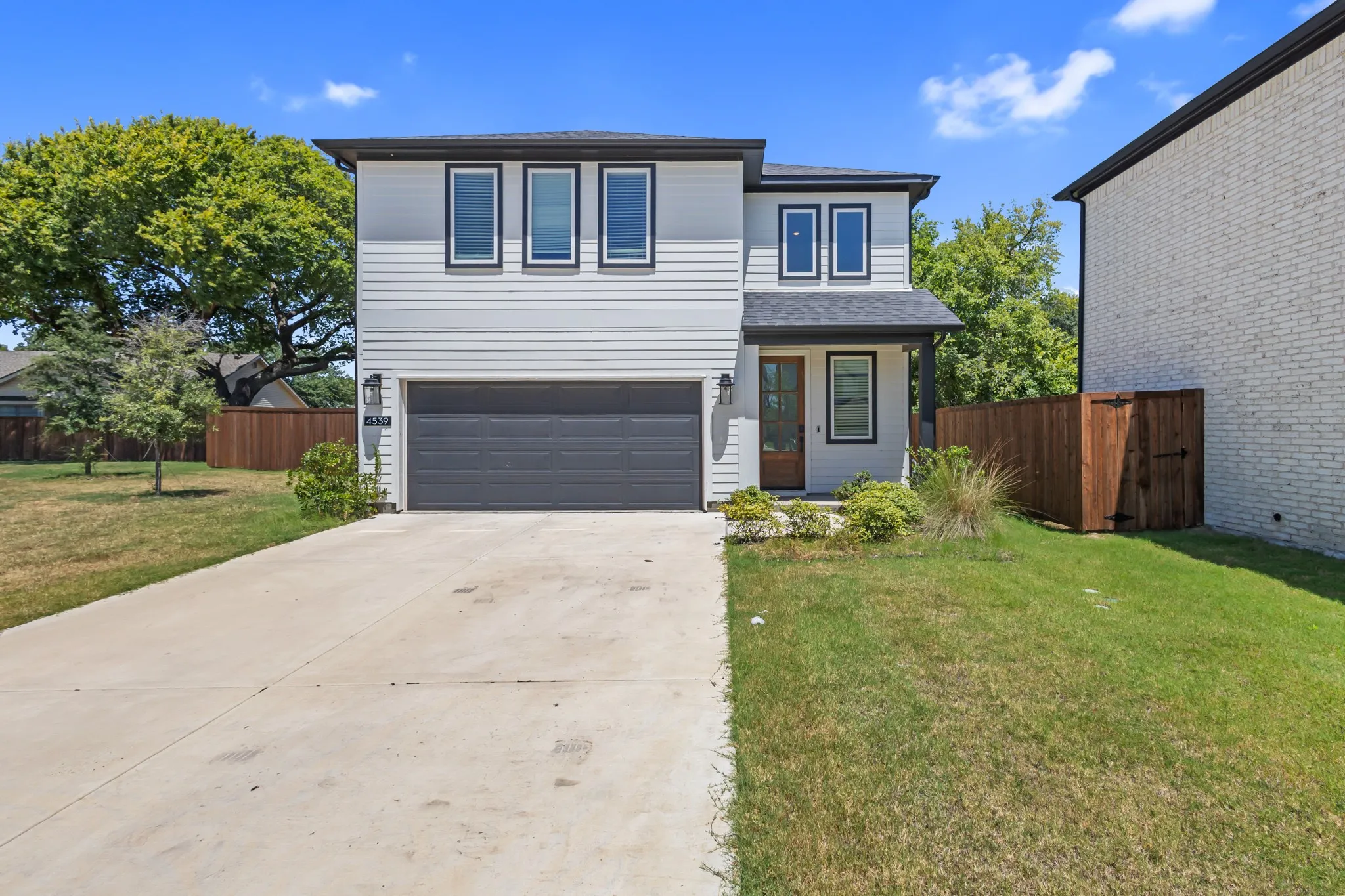 Two-story residence featuring light siding, dark trim, an attached two-car garage, and a concrete driveway