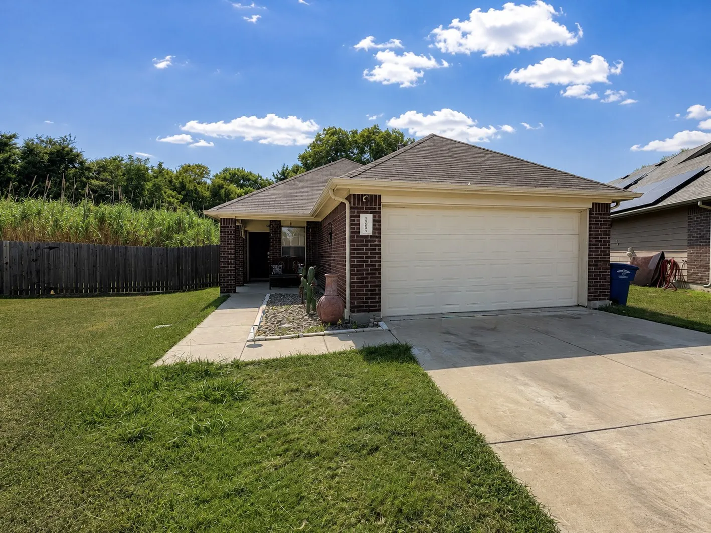 Brick exterior with an attached garage, concrete driveway, and front walkway leading to the entry