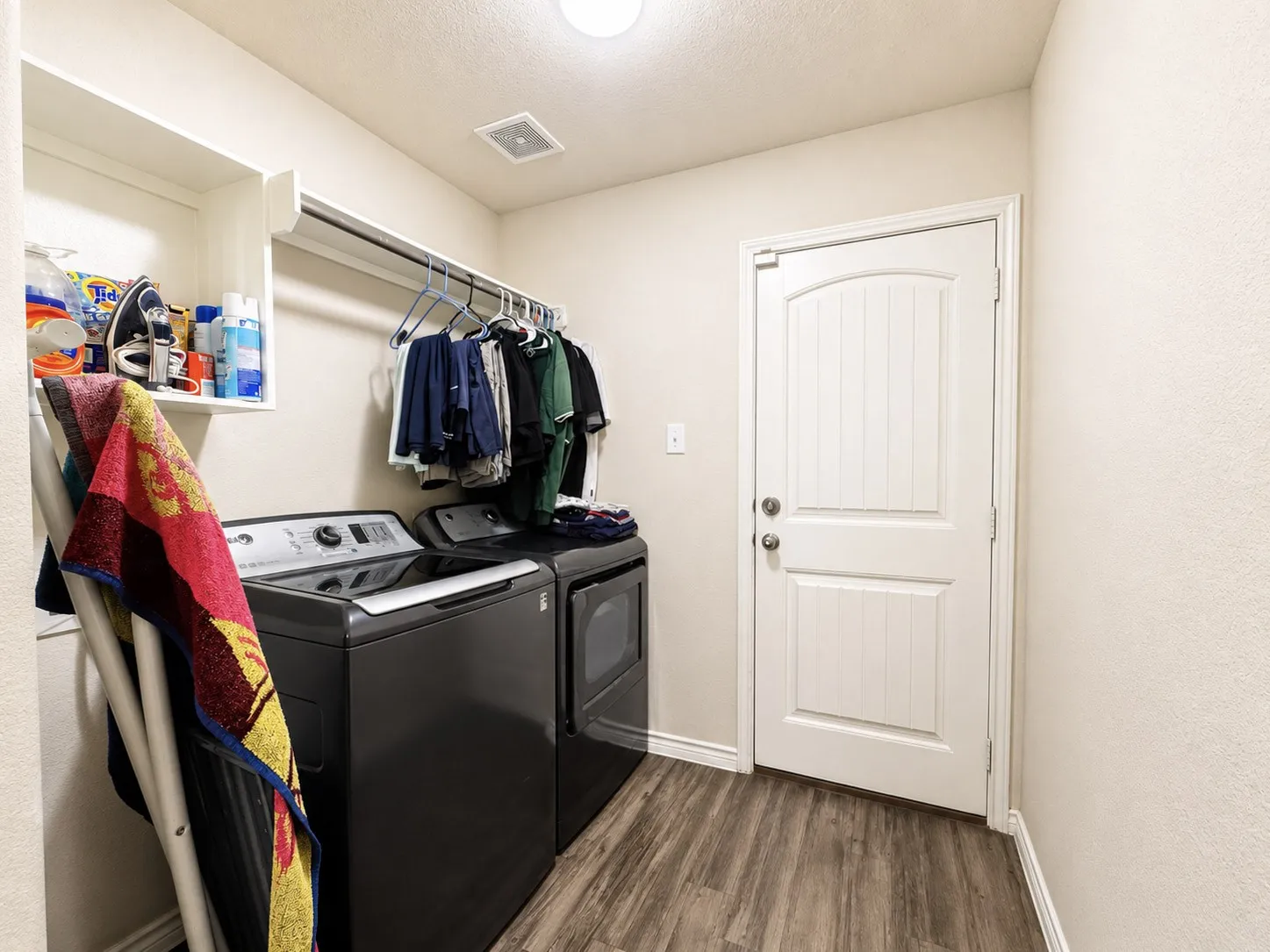 Laundry area featuring wood-finish flooring, built-in shelving, and a hanging rod
