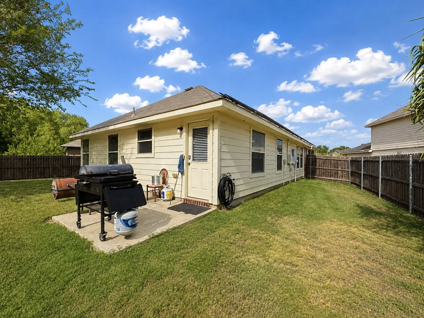 Expansive fenced backyard with a concrete patio pad and a single entry door