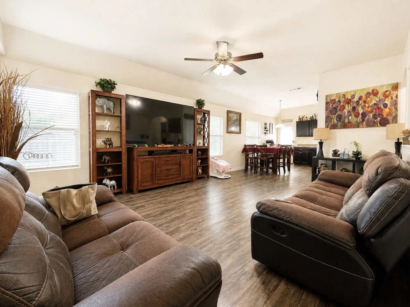 Spacious living area featuring wood-finish flooring, a ceiling fan with integrated lighting, and vaulted ceilings