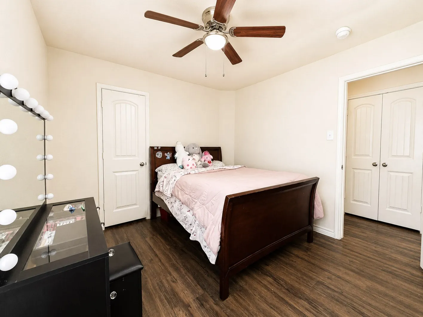 Wood-finish flooring throughout, ceiling fan with integrated lighting, and white panel doors