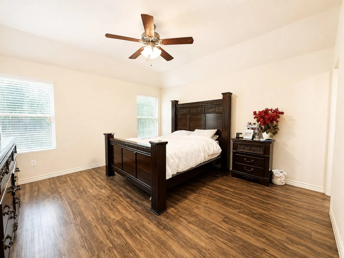 Vaulted ceiling with a ceiling fan light fixture, wood-finish flooring, and two windows