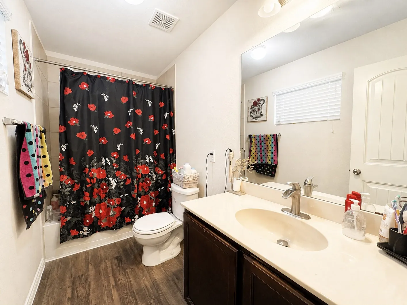 Wood-finish flooring, single vanity with a light-toned countertop, and recessed lighting