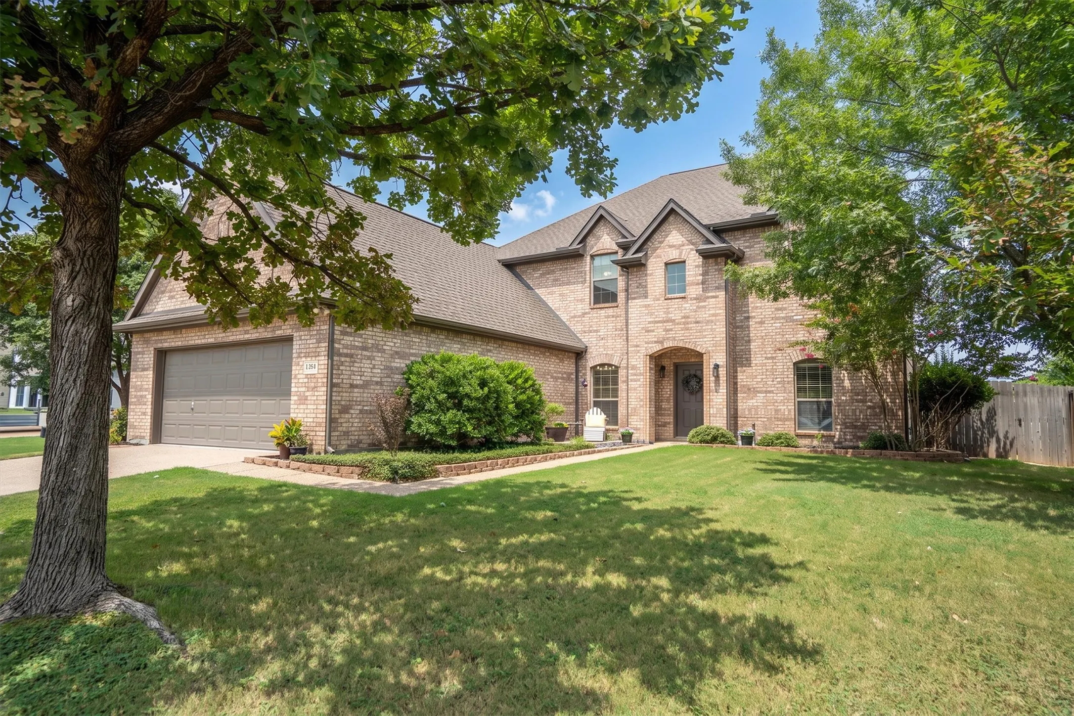 Charming two-story brick home with mature shade tree and manicured front lawn
